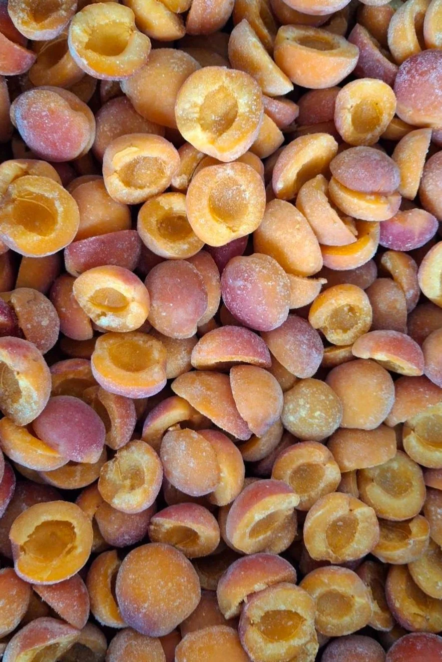 Frozen salted peaches in close-up, showing peach halves with some ice crystals on surface.