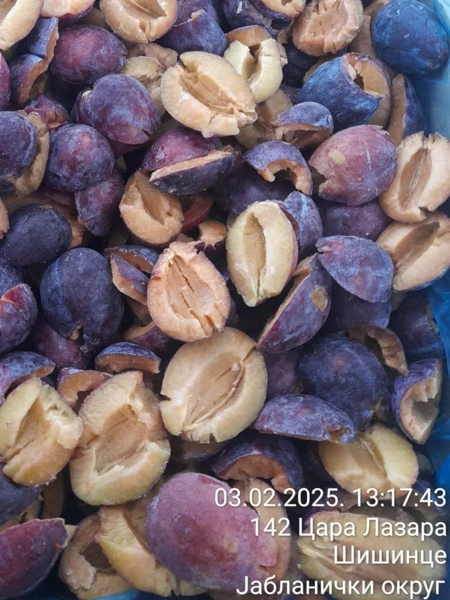 Close-up of cracked and whole hazelnuts with purple and brown shells, some with a bluish tint, on a surface.
