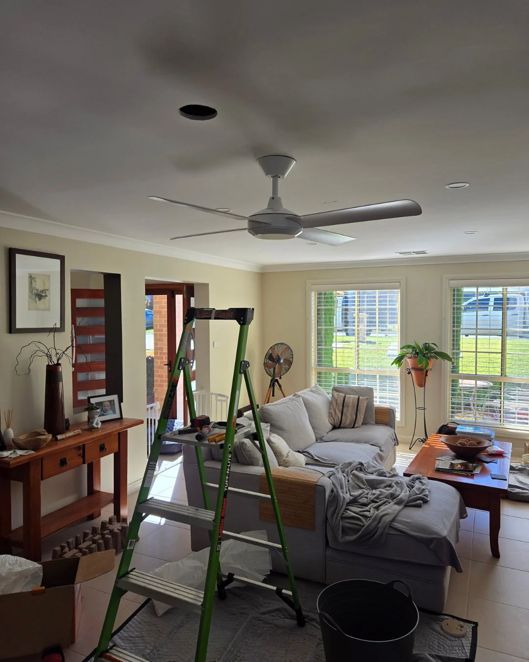 Ceiling fan installation underway in the living room of a Harrington Park home, showing the electrician's ladder and the fan position