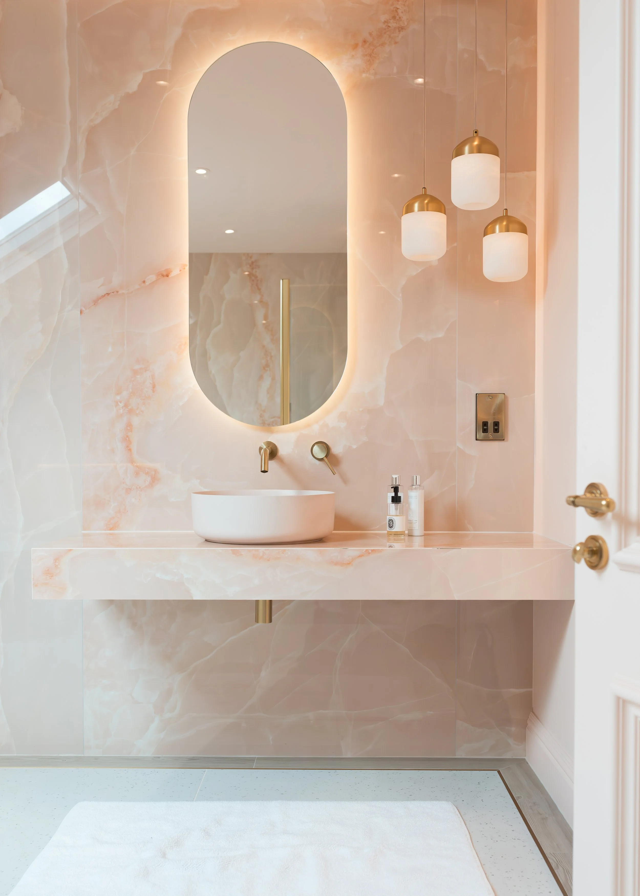 Pink onyx en-suite. Large format tiles. Flowing recessed shelves. Mitred edges. Bespoke vanity.