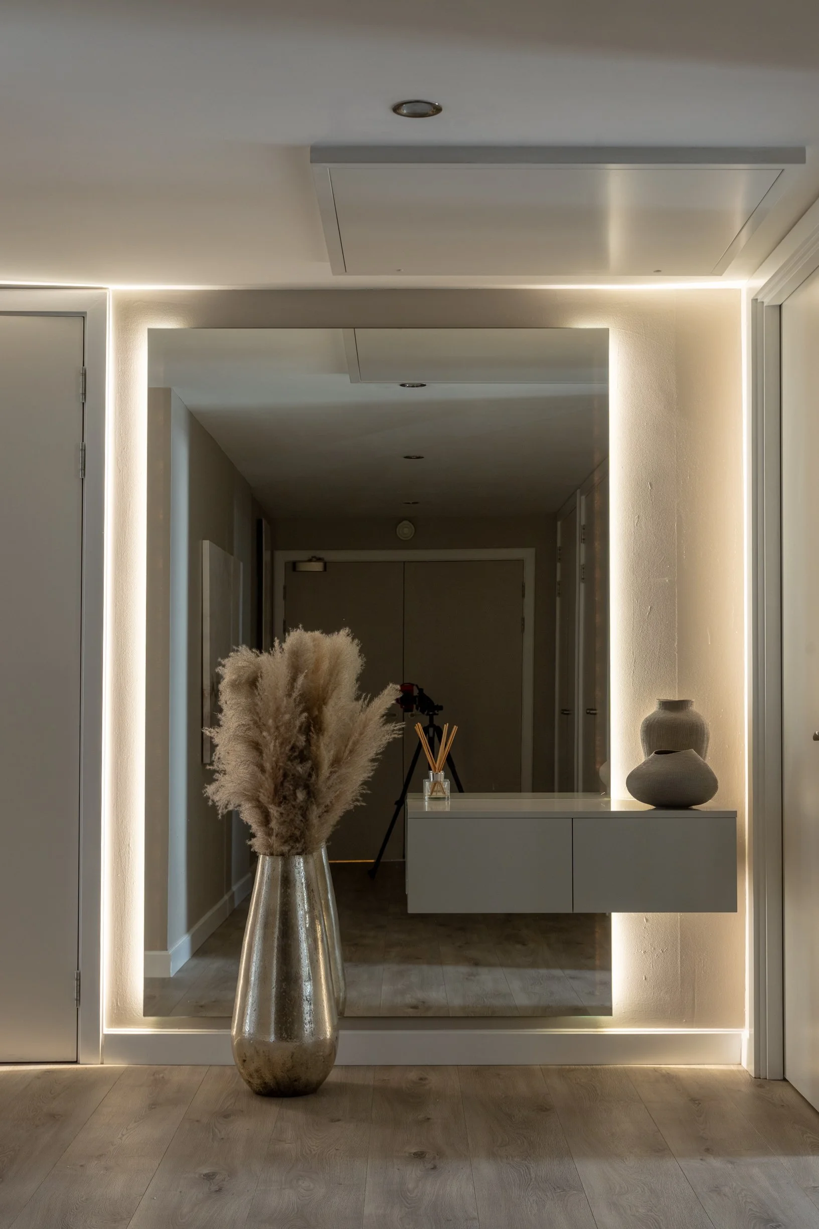 Penthouse apartment kitchen. Oversized, split level kitchen island. Breakfast station with pocket doors. LED lighting. TV wall. Bespoke, illuminated mirror. Large format floor tiles.