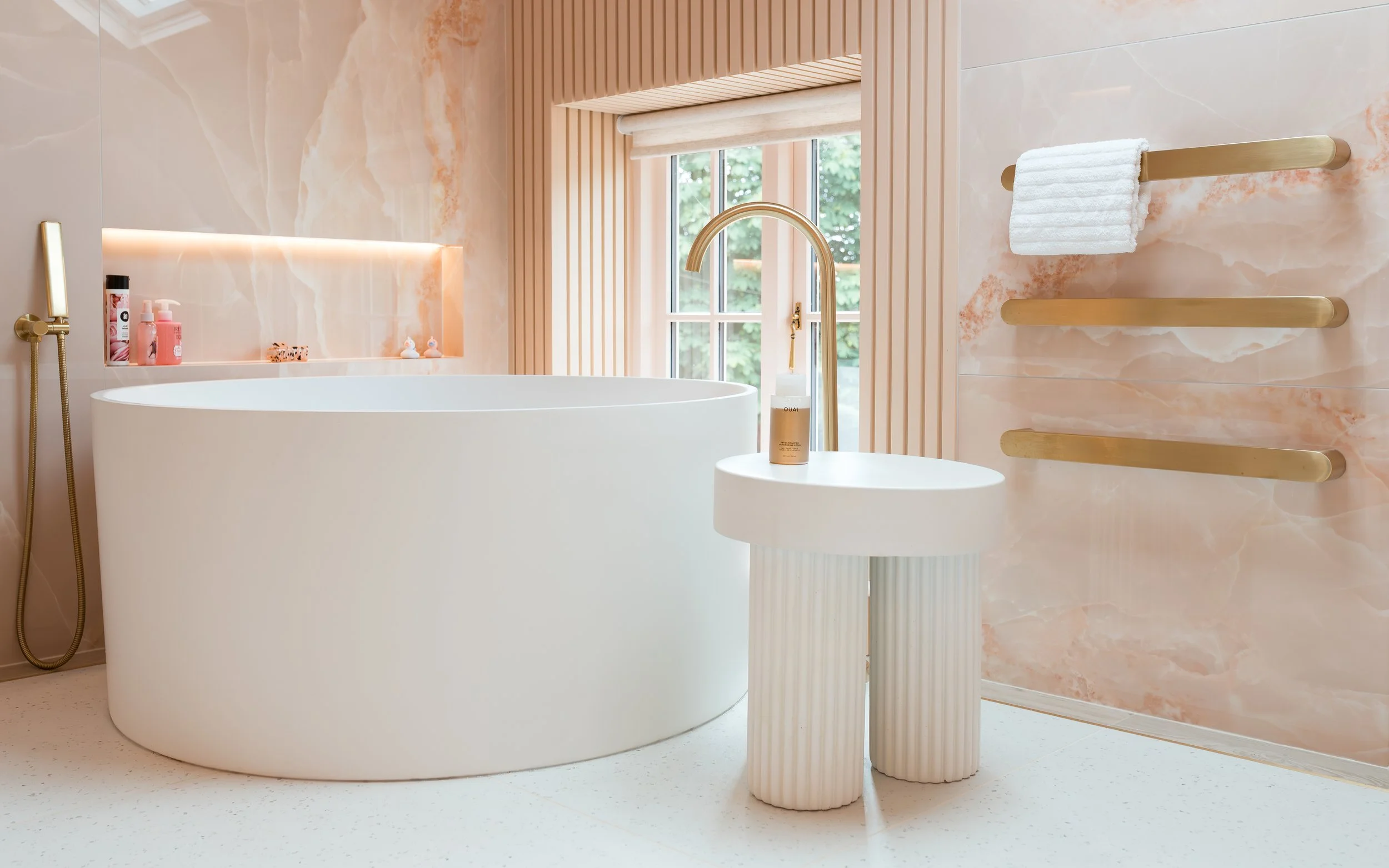 Pink onyx en-suite. Large format tiles. Flowing recessed shelves. Mitred edges. Bespoke vanity.