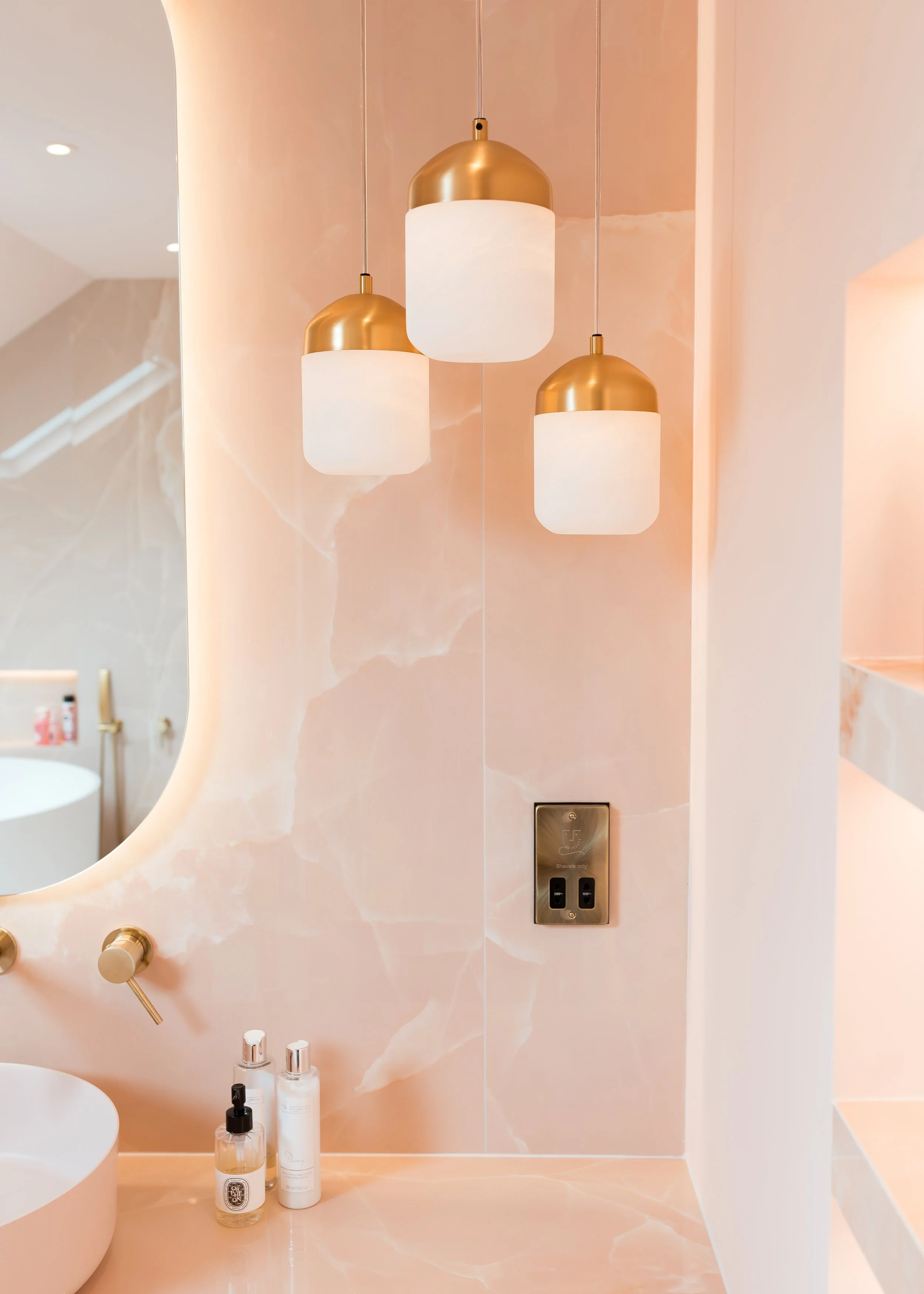 Pink onyx en-suite. Large format tiles. Flowing recessed shelves. Mitred edges. Bespoke vanity.