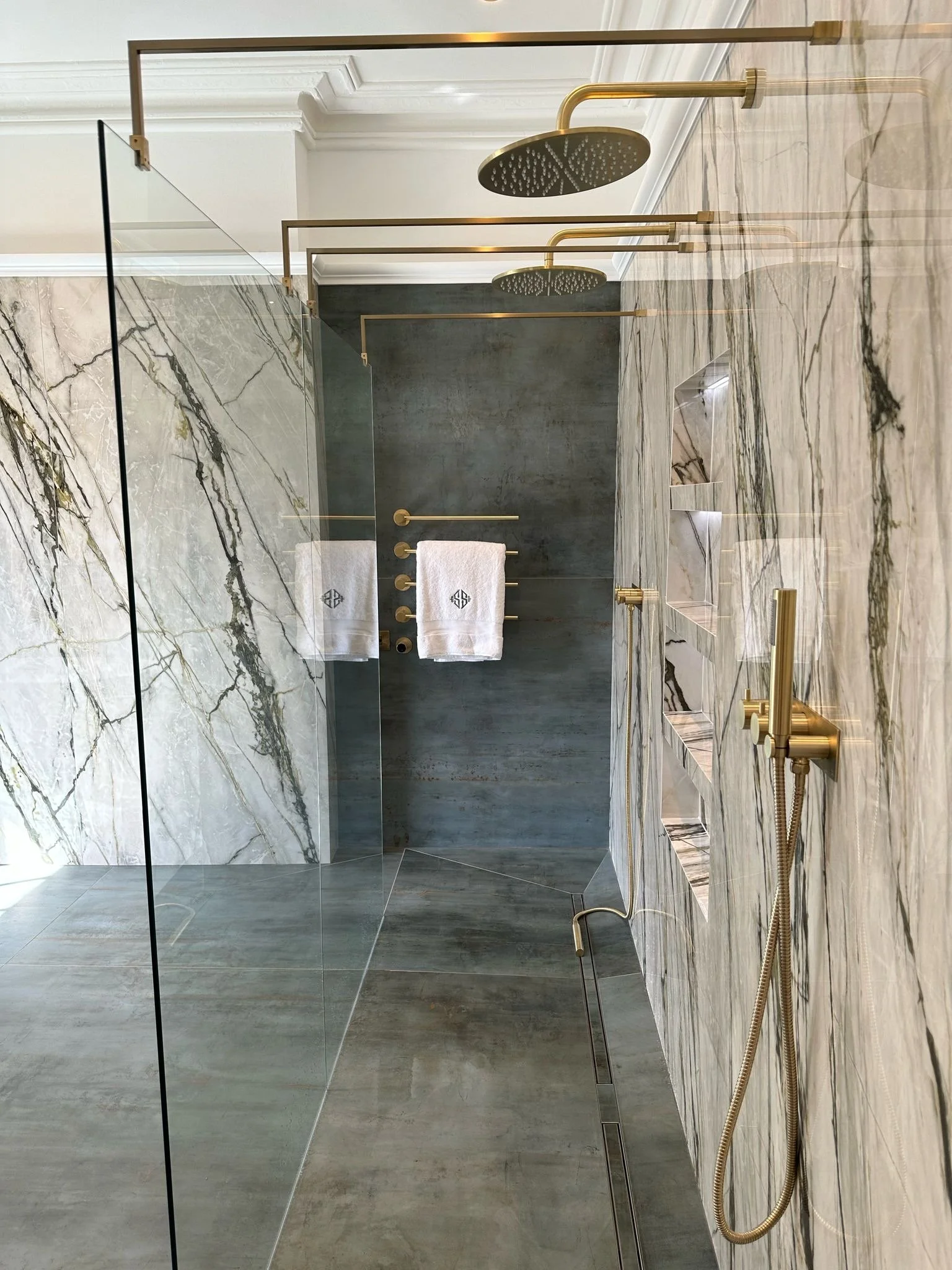 Large family bathroom. Double shower. Large format tiles. Recessed shelves. Mitred edges. Double vanity. Bespoke double basins. Illuminated mirrors. Free standing bath. Floor mounted bath tap.