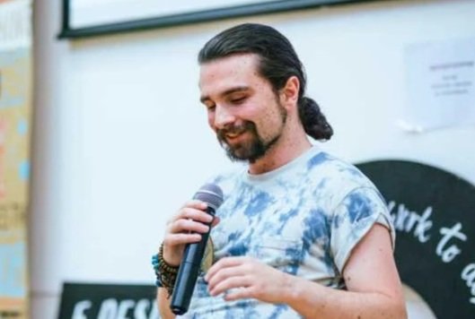 Scott McAulay - holding a microphone speaking at sustainability event.