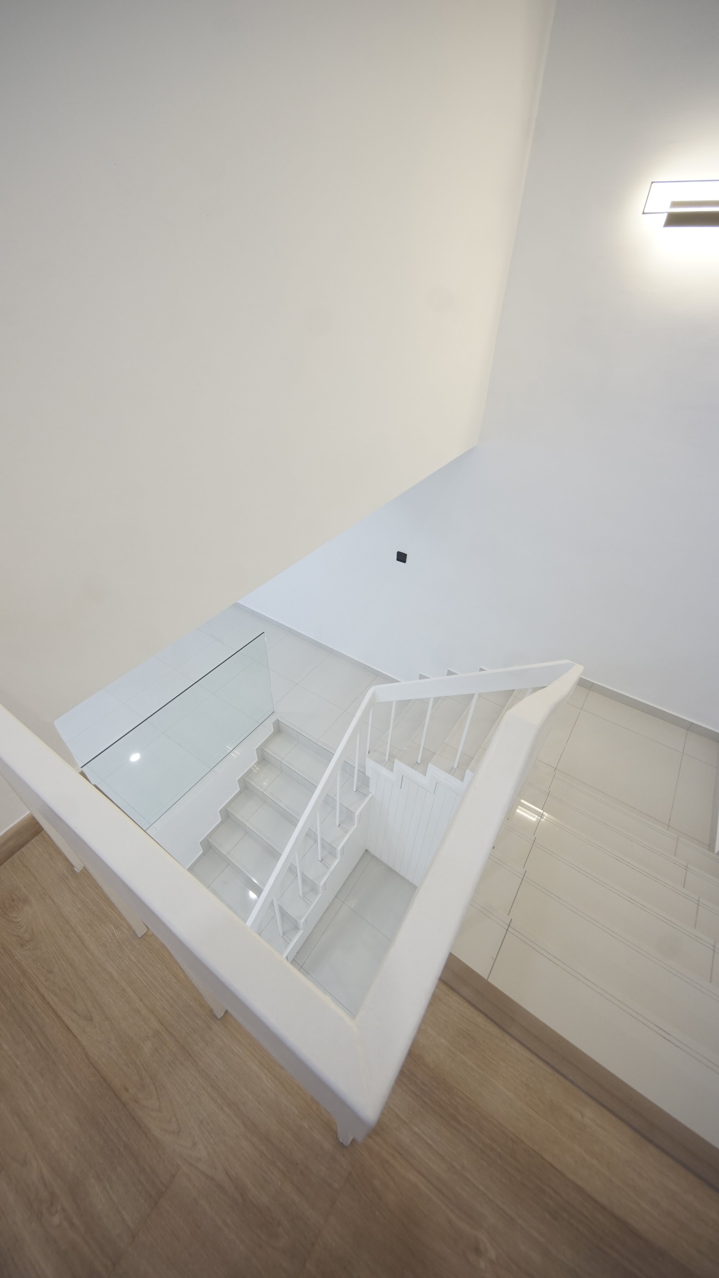 Modern white staircase with glass railing and wooden floors in a well-lit interior space.