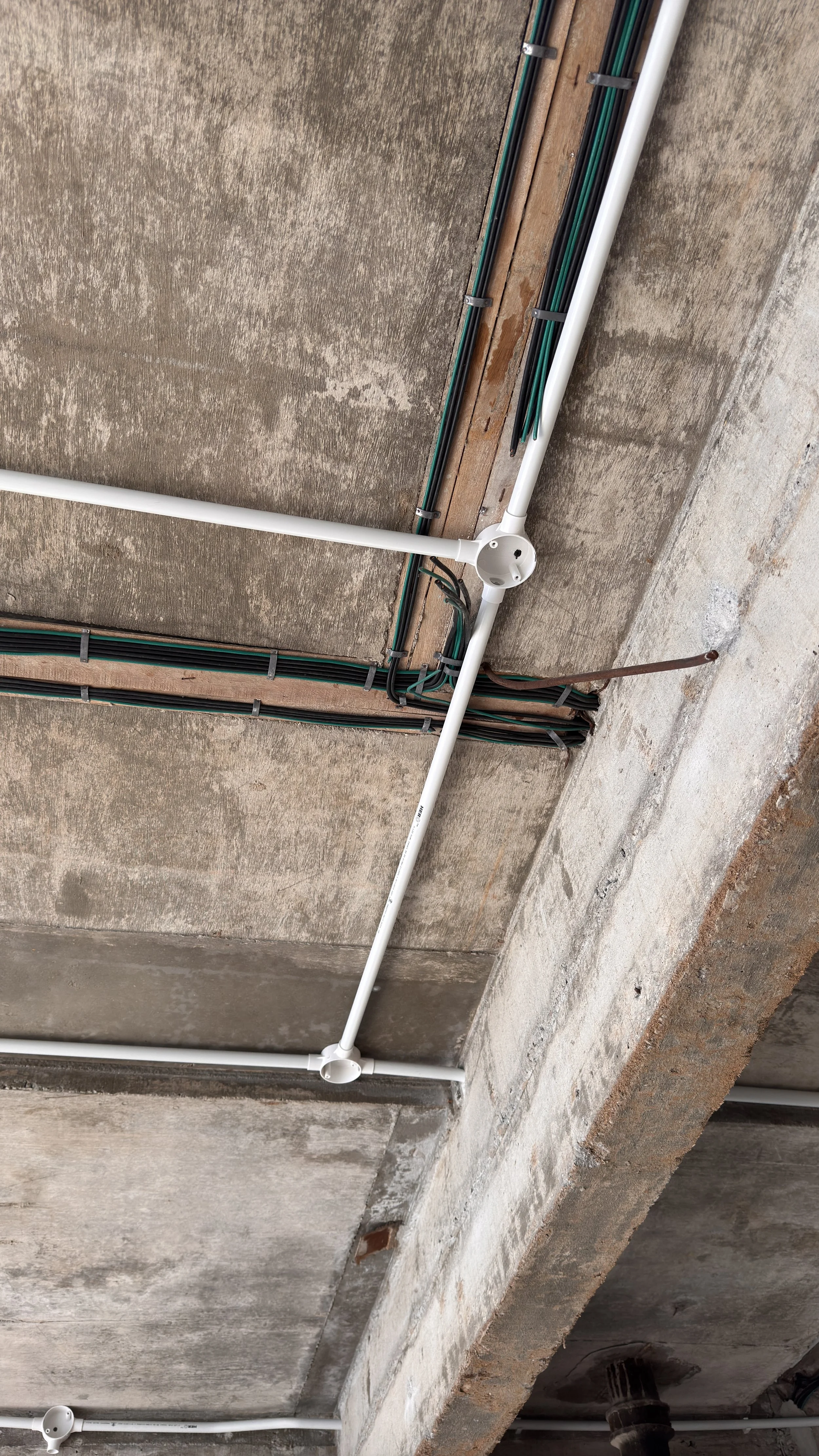 Exposed concrete ceiling with white pipes and electrical wiring