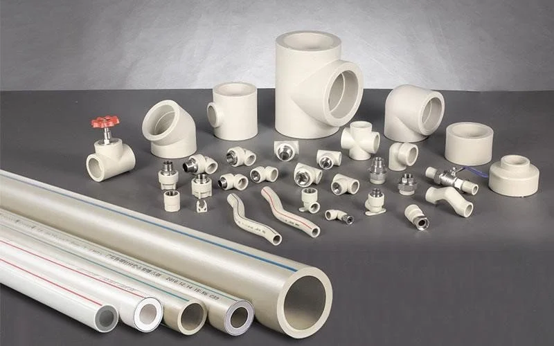 Array of various PVC and metal plumbing fittings and pipes displayed on a gray background.
