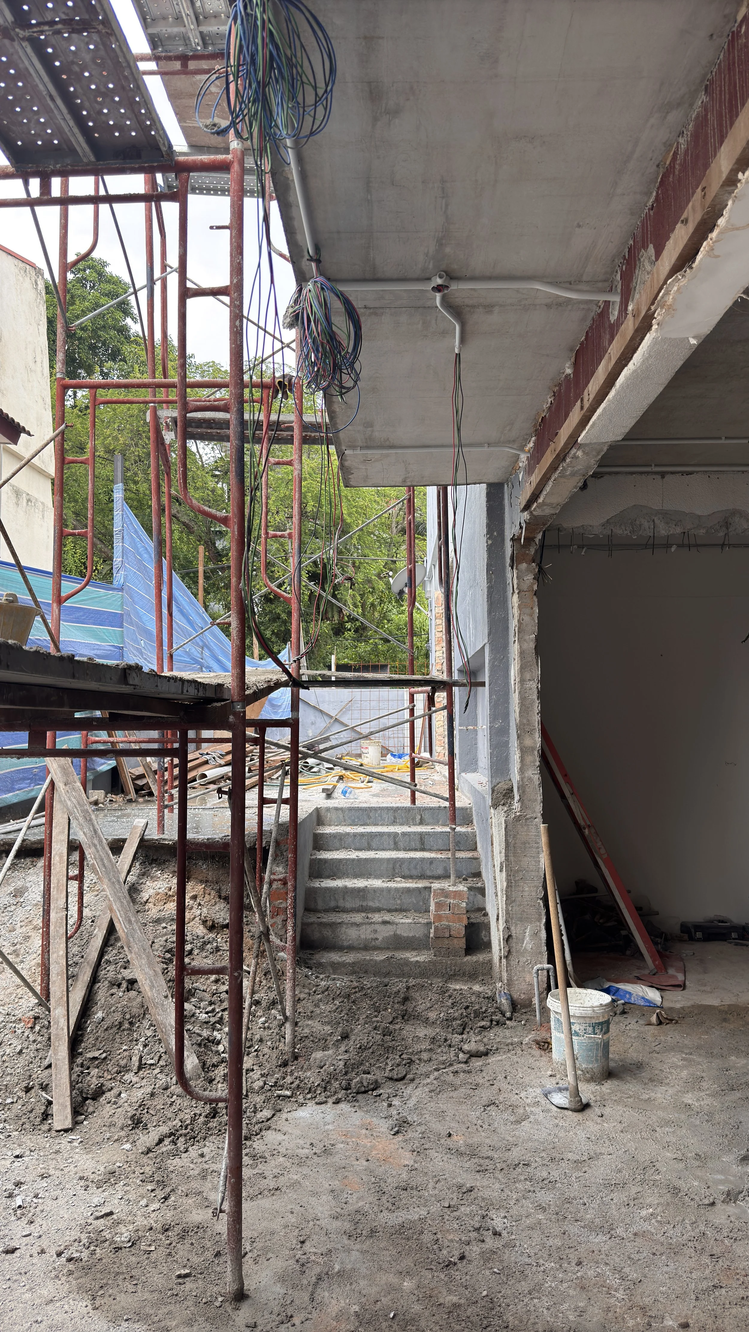 Construction site with exposed scaffolding, concrete, stairs, and wiring.