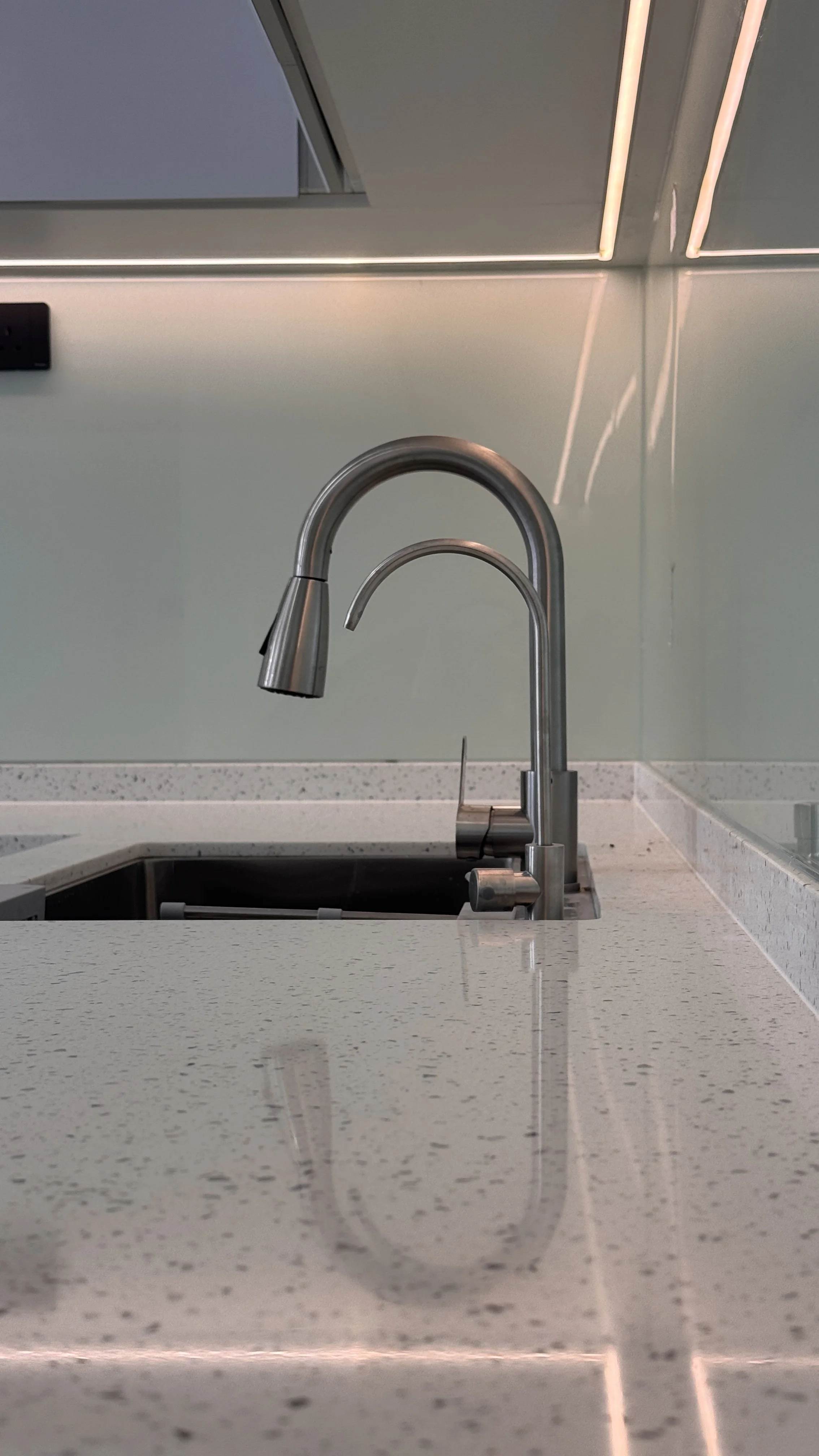 Modern kitchen sink with stainless steel faucet and light-colored countertop in a contemporary setting.
