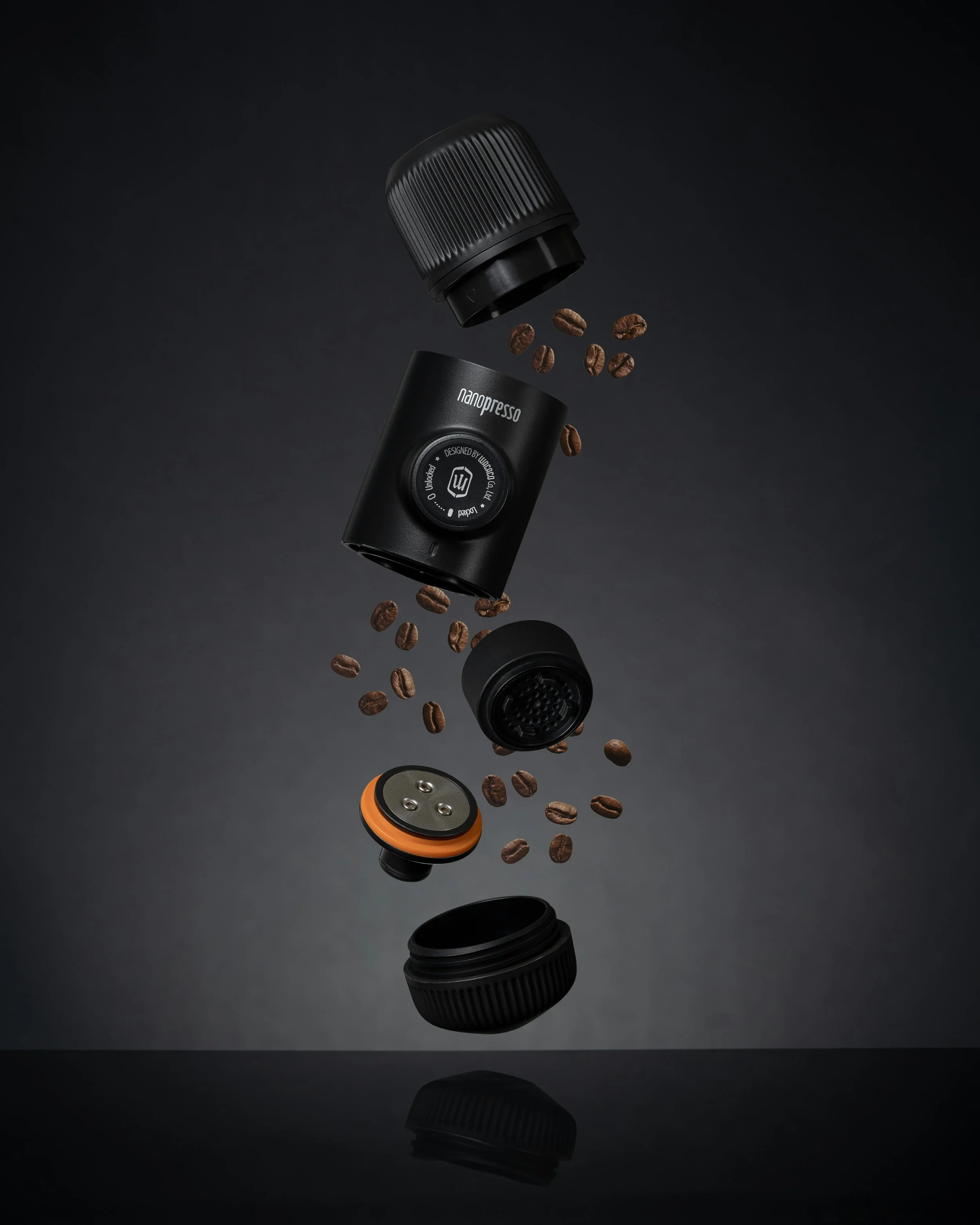 Disassembled coffee grinder with beans floating around in a dark background.