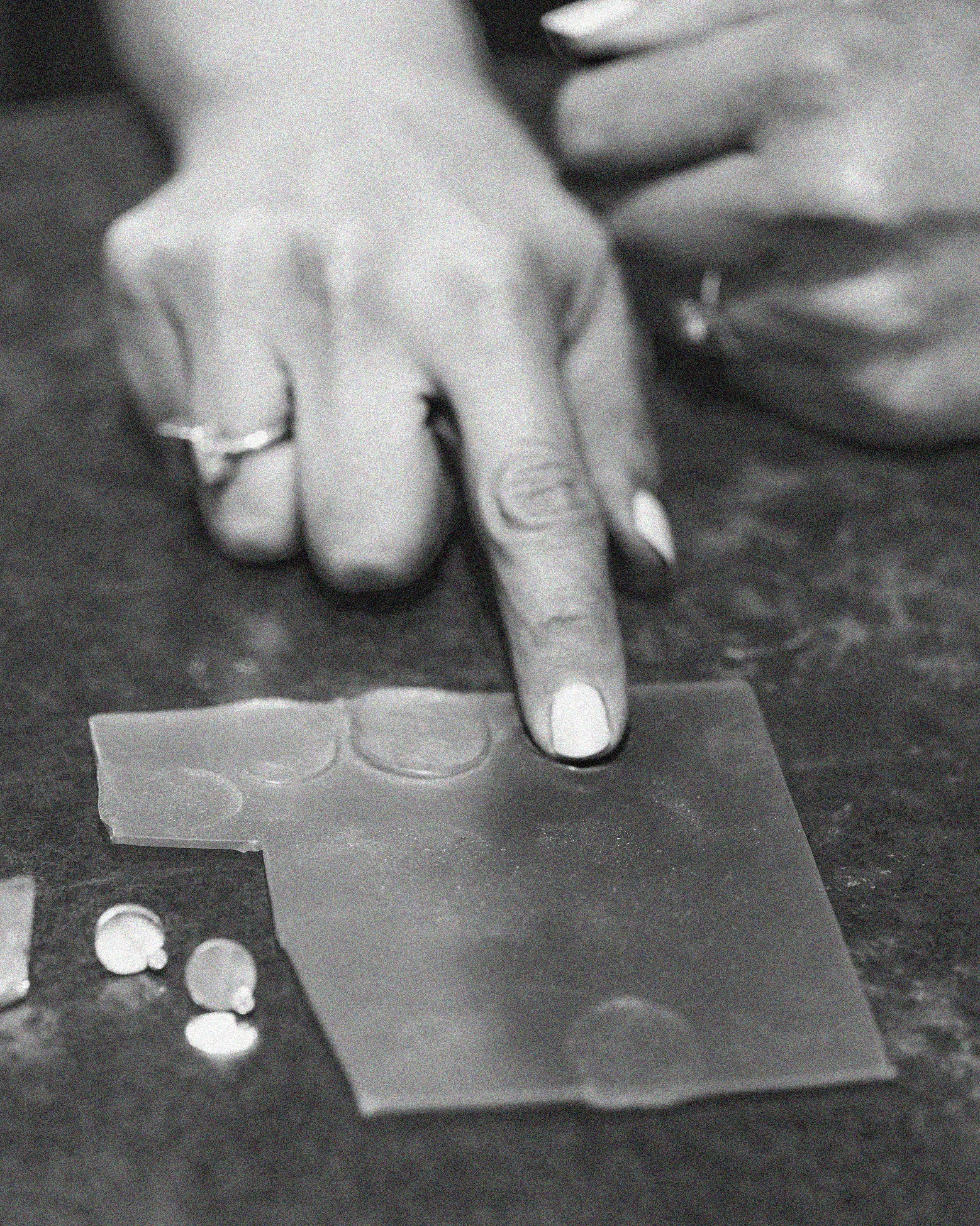 Een hand met een ring wijst naar een stuk transparant papier waarop enkele muntjes liggen.