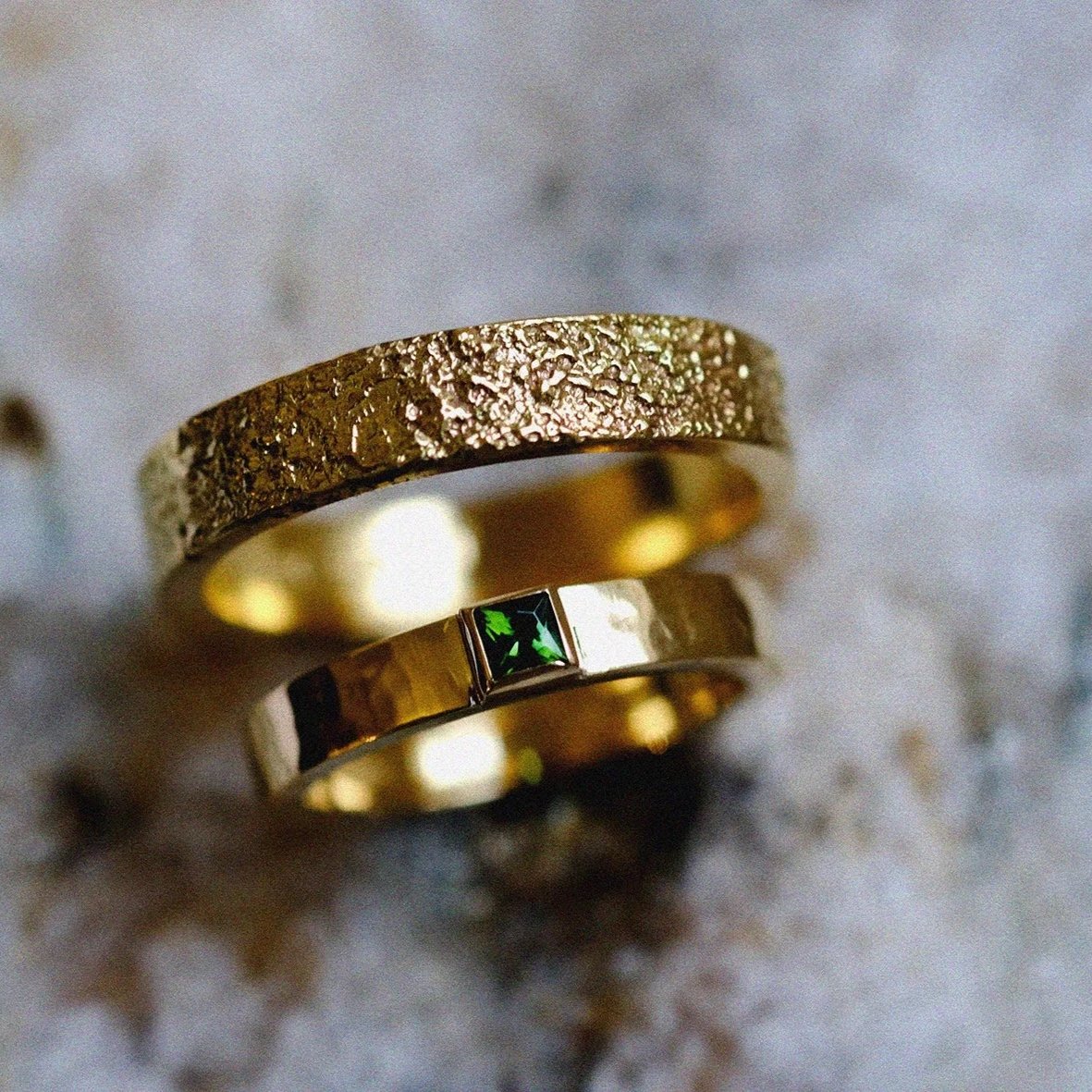 Uniek ontworpen trouwringen in 18k geel goud afgewerkt met een groene saffier