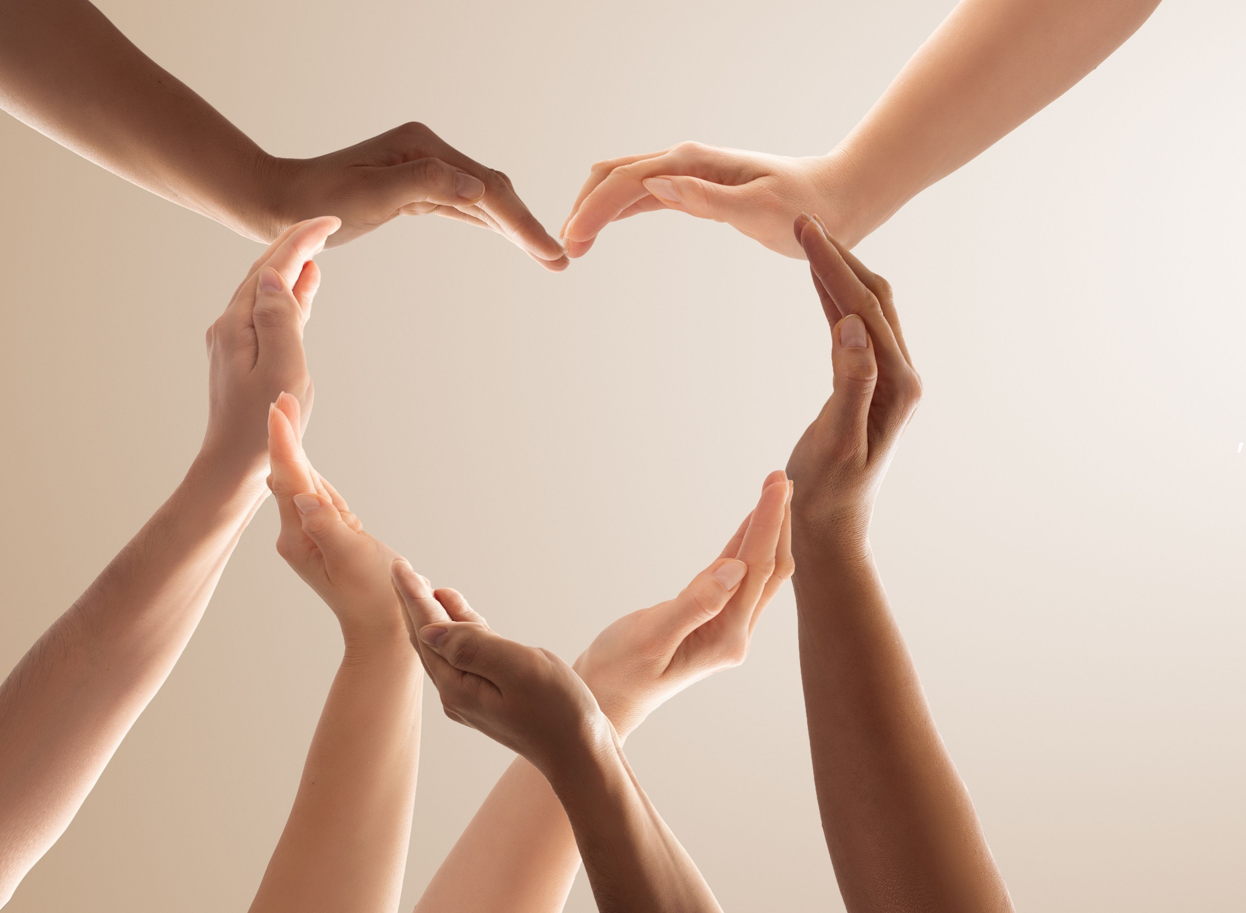 Flere hender som danner en hjerteform mot en lys bakgrunn.