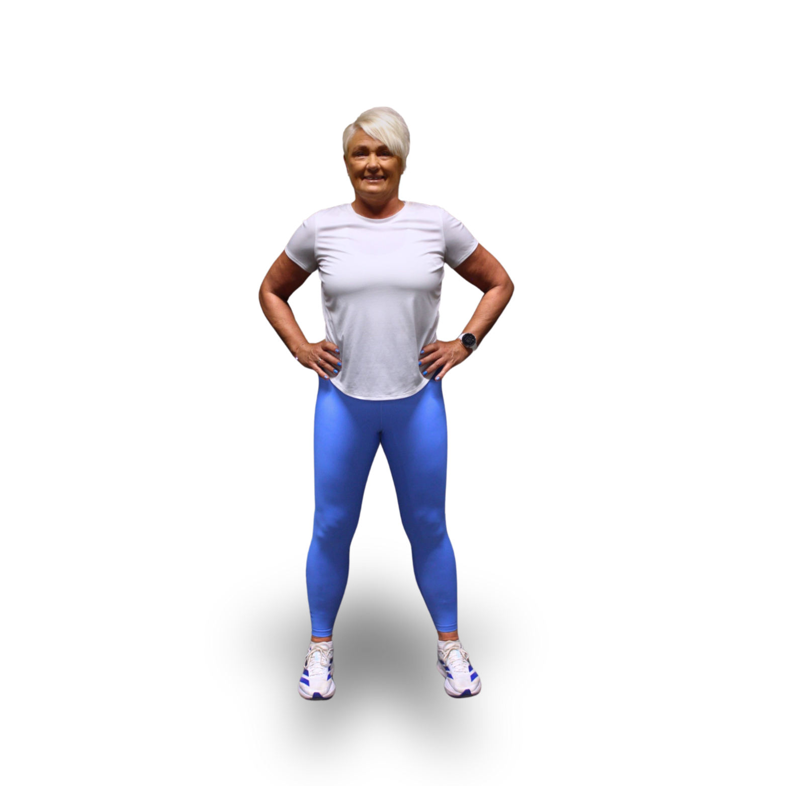 Person i treningsklær står med hendene på hoftene, iført hvit t-skjorte og blå leggings. Bakgrunnen er svart.