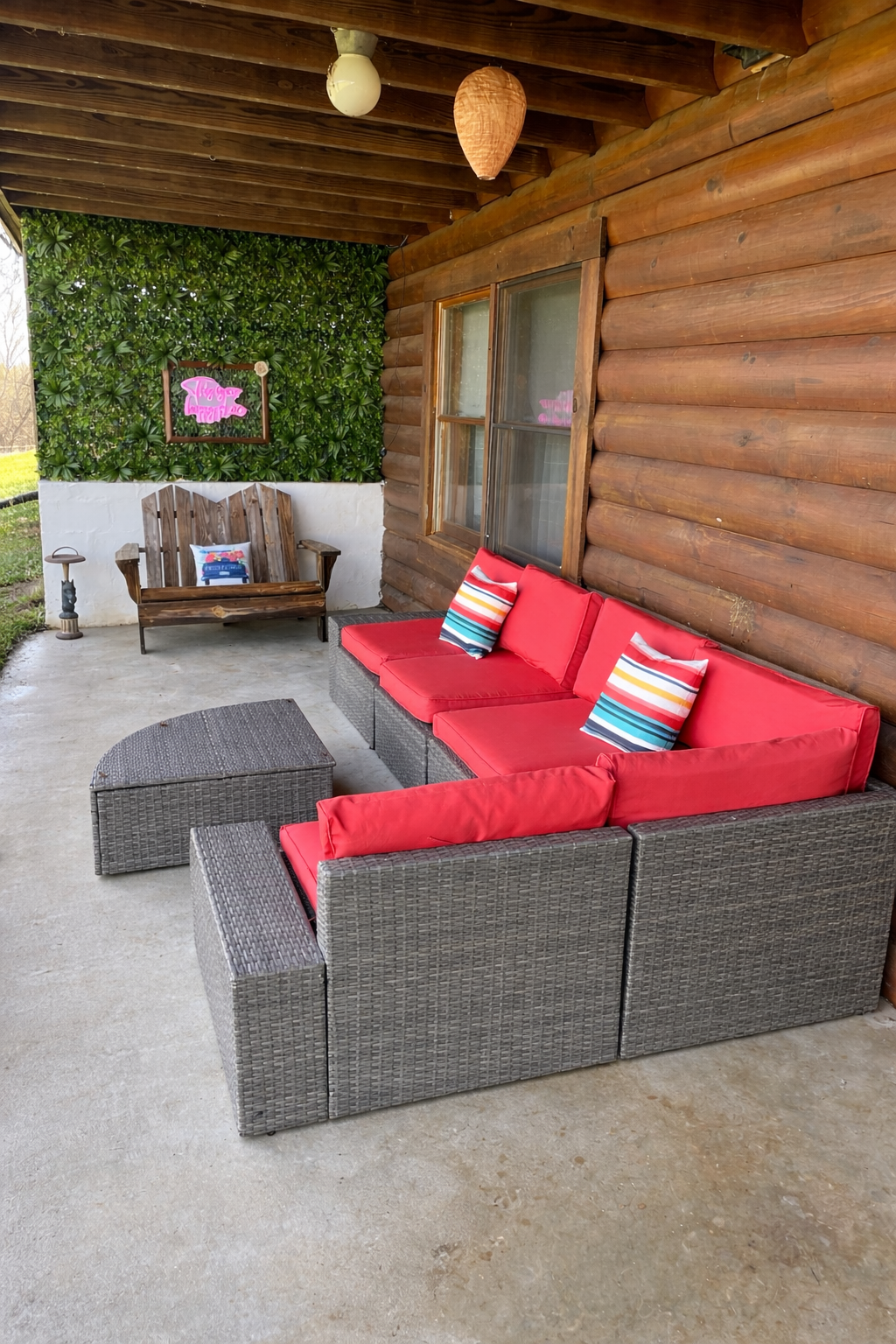 Covered outdoor patio with red sectional sofa and living green wall at Creekside Crafters women's retreat in Watertown, Tennessee