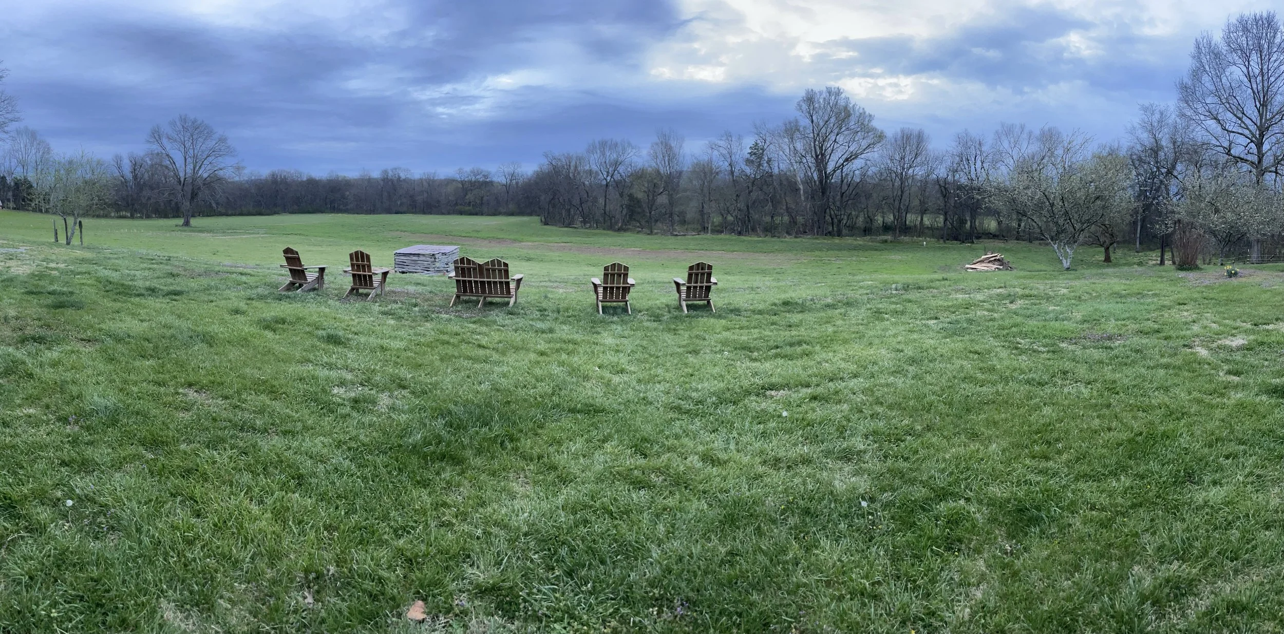 Adirondack chairs overlooking open green fields and scenic sky at Creekside Crafters retreat on 15 acres in Watertown, Tennessee
