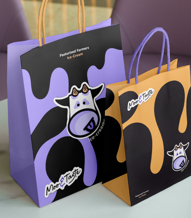 Two colorful shopping bags with cow designs and ice cream branding, one purple and one orange, on a table.