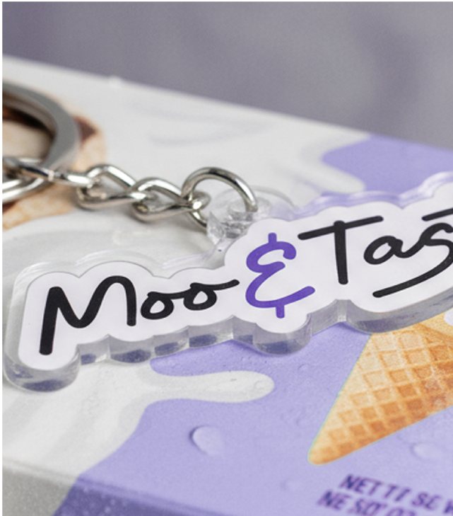 Close-up of a Moo & Tasty ice cream brand keychain on top of ice cream packaging.