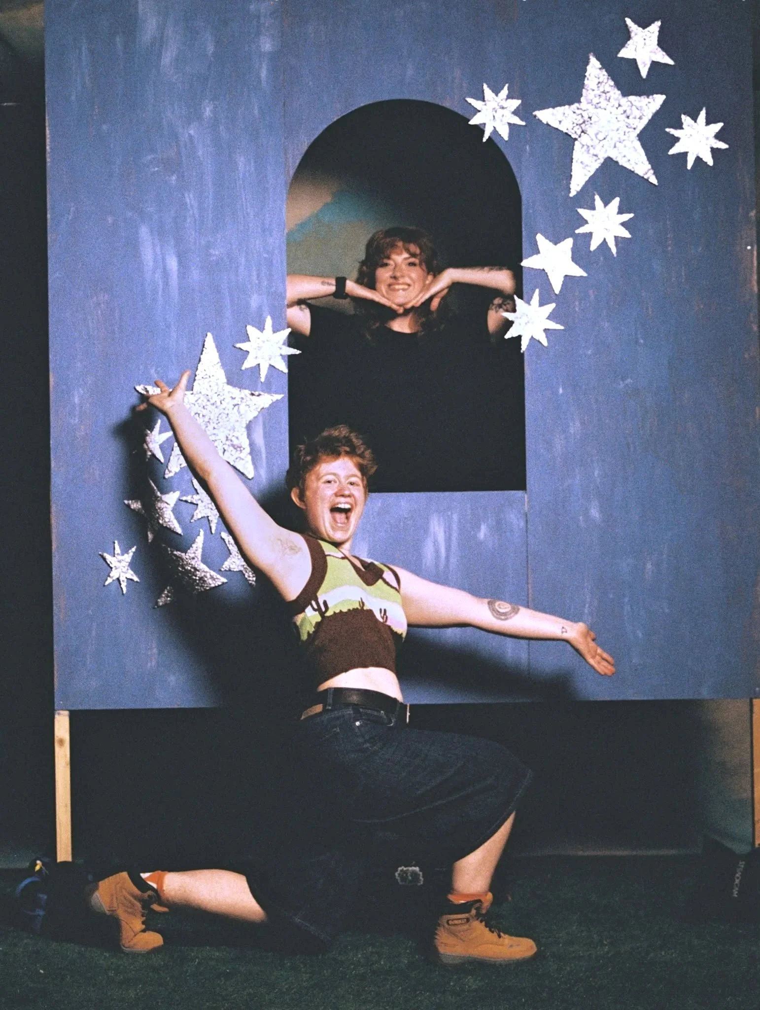 Neon Roadies Em and Marta posing in a blue arch decorated with silver stars