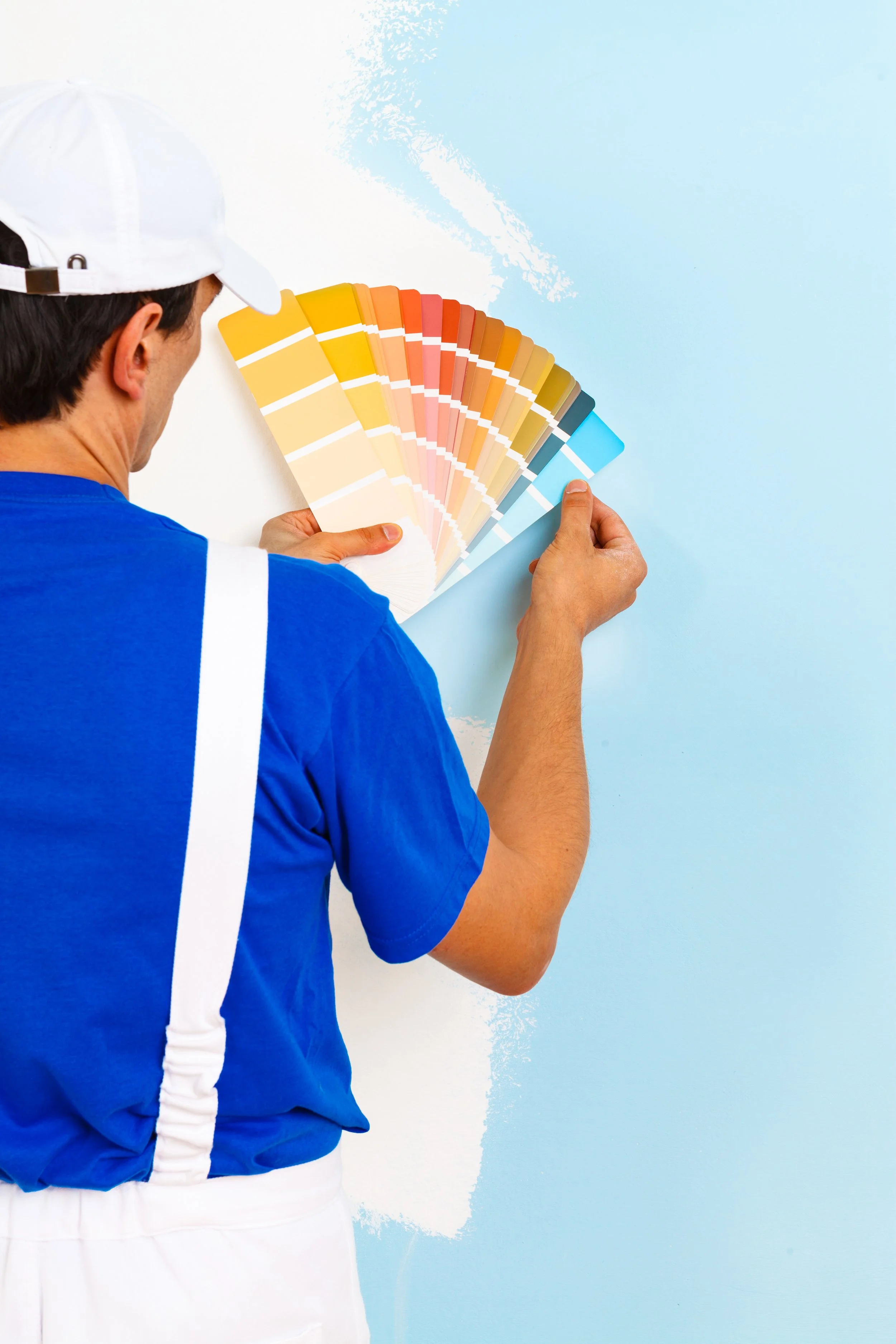 A person holding a paint color fan deck while selecting paint for a wall.
