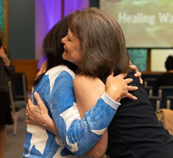 Three women smiling and laughing outdoors.