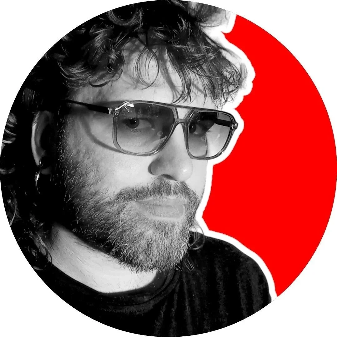 Schwarz-Weiß-Foto eines Mannes mit lockigem Haar, Brille und Earring, vor rote und weiße Hintergrund.