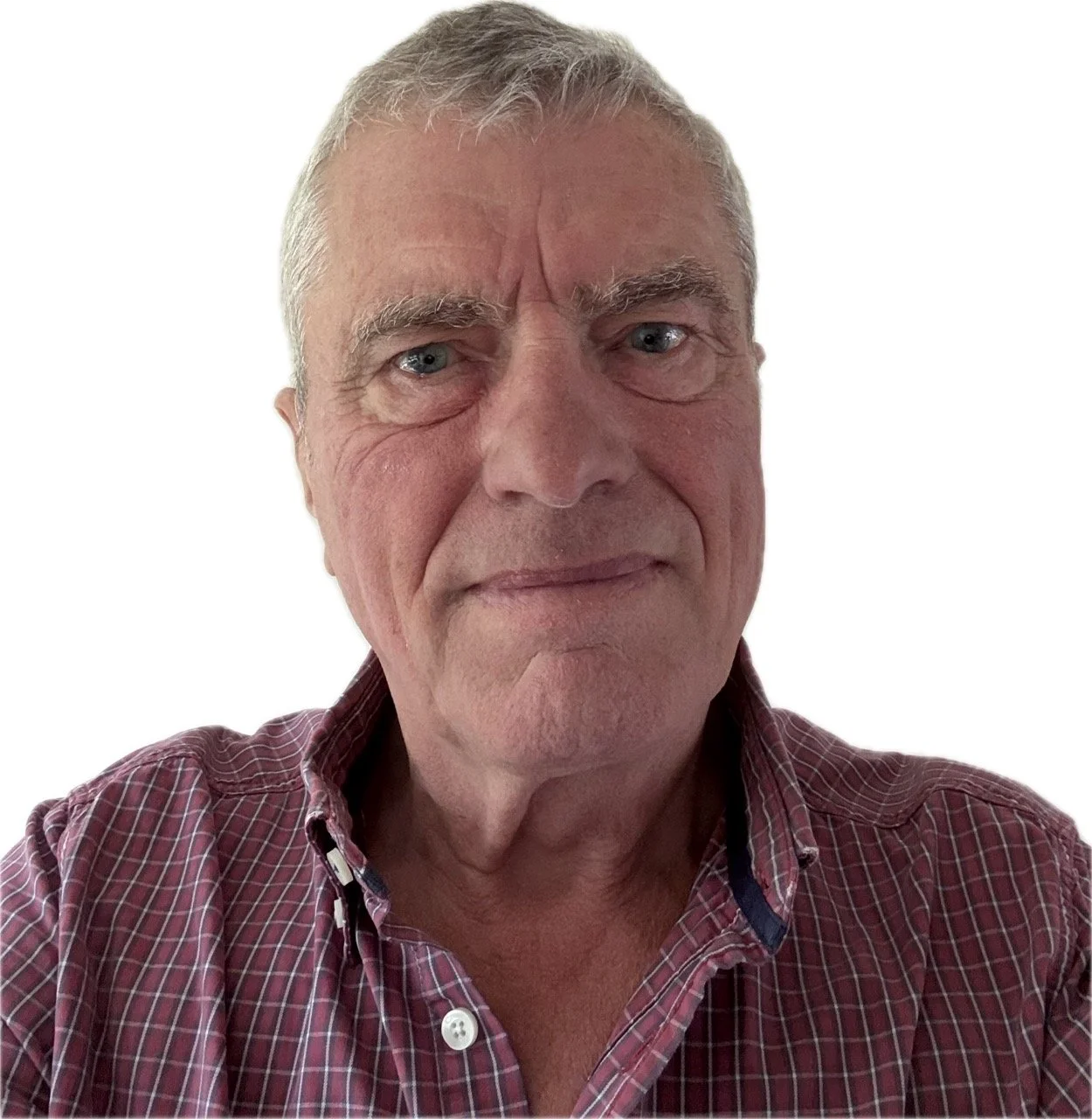 Close-up photo of an older man with light grey hair, blue eyes, and wearing a red and white checkered shirt, against a plain white background.