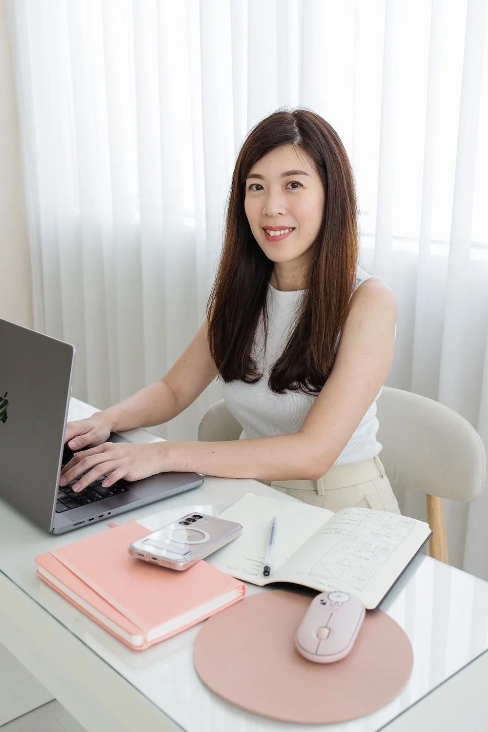 Website designer, Fiona Lee, sitting at her desk, working on her laptop