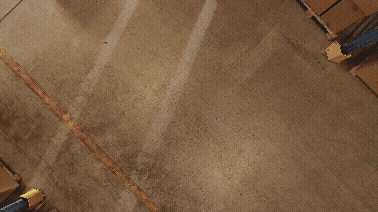 Empty parking lot with marked parking spaces and a cardboard box in the corner.