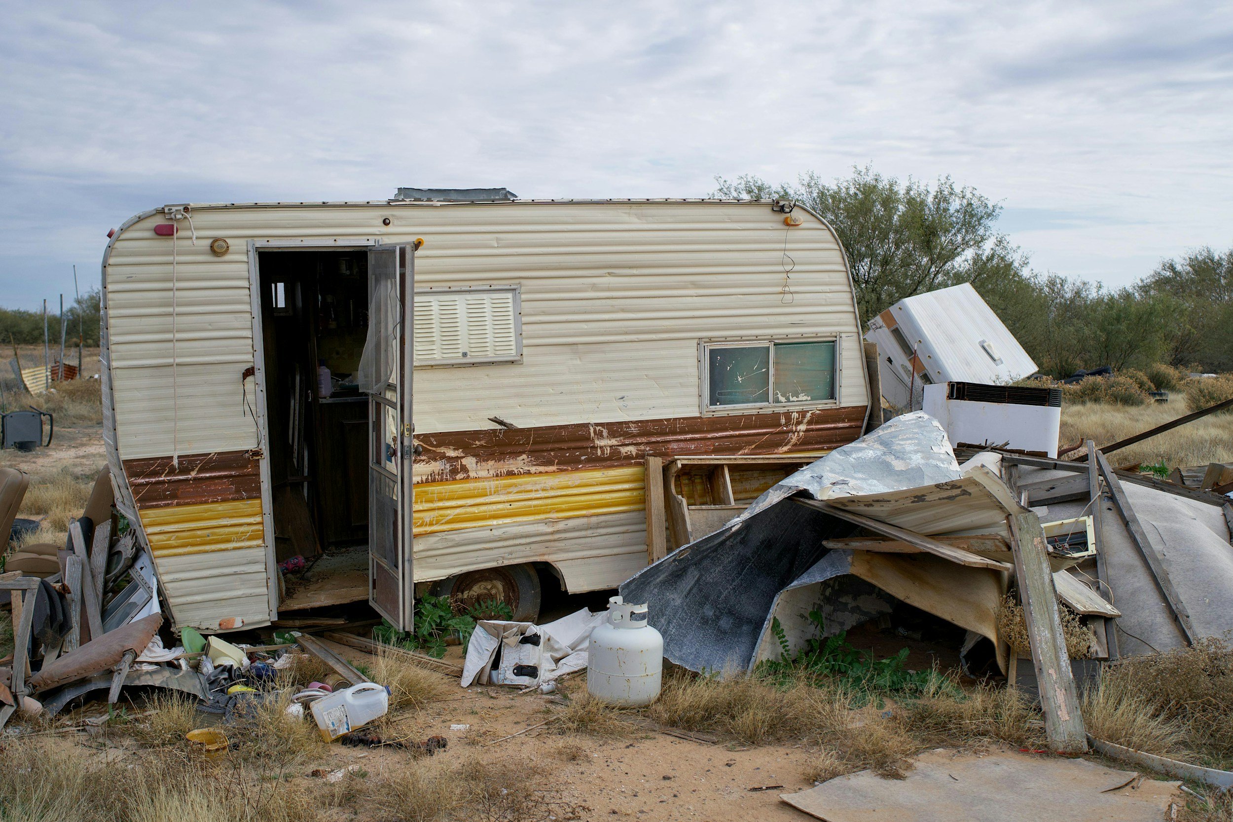 old trailer with yard debris surrounding that needs to have junk hauled away