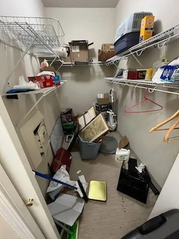 Cluttered walk-in closet with shelves, boxes, and miscellaneous items.