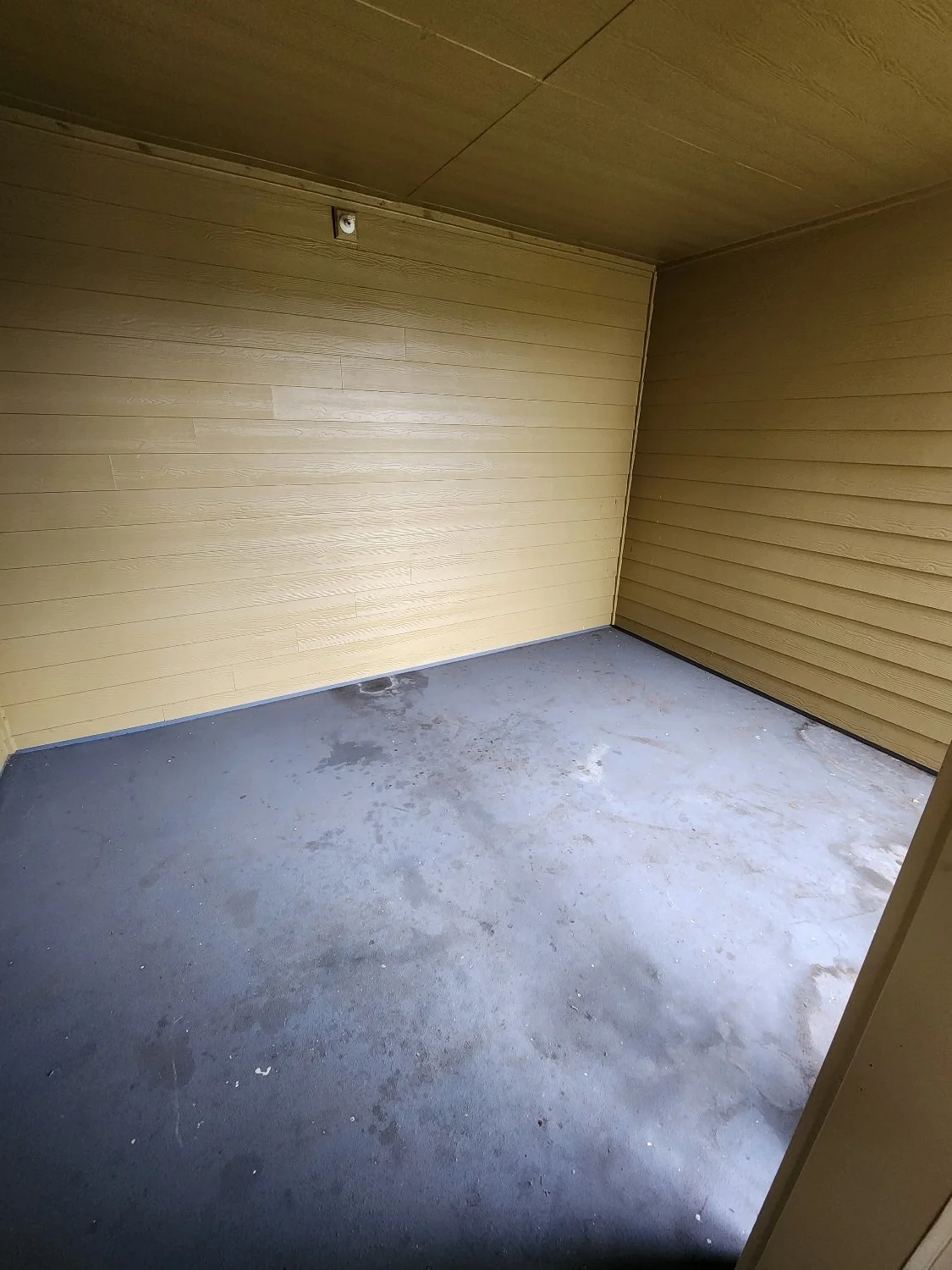 Empty porch with yellow wooden walls and concrete floor