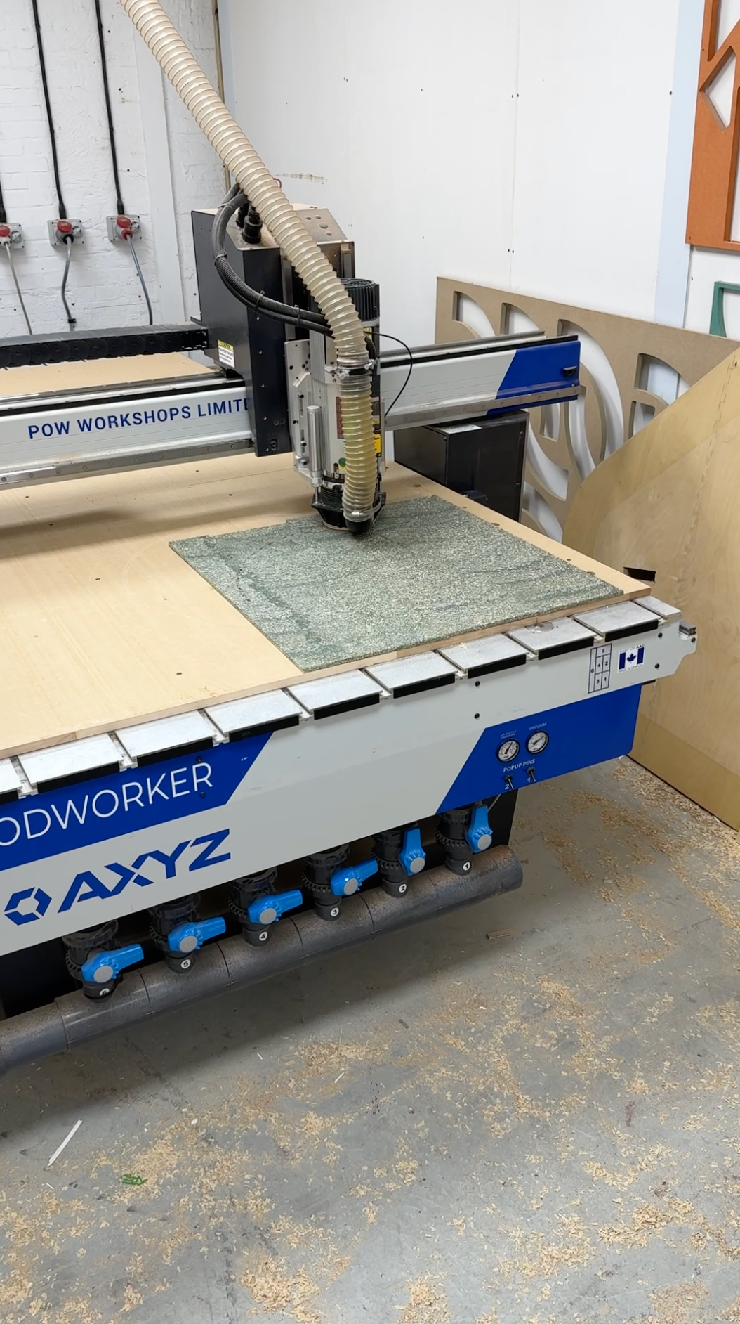 A CNC router machine in a workshop, cutting a green Cupsan panel