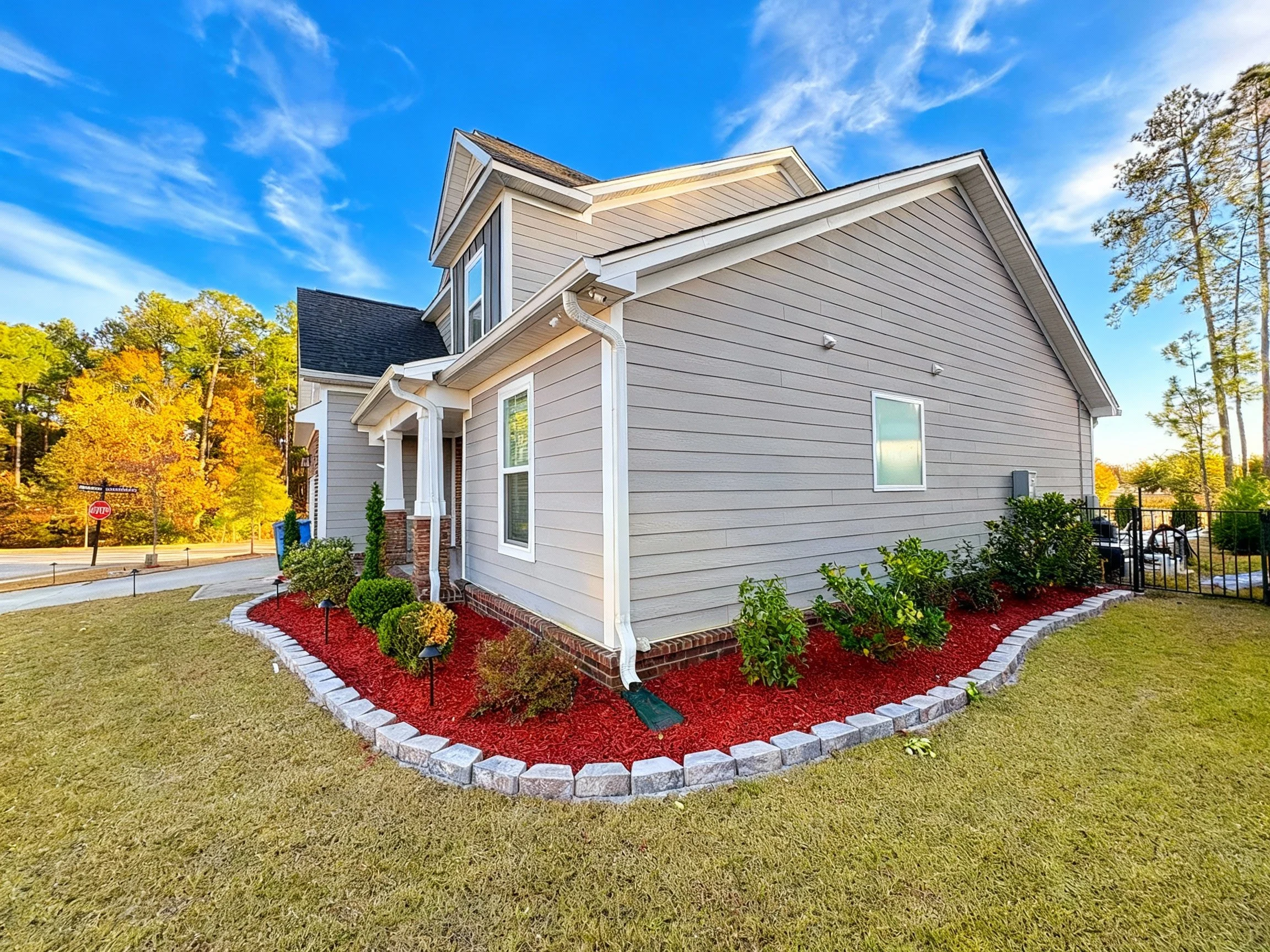 Red mulch bed with concrete garden stones encasing the plant bed