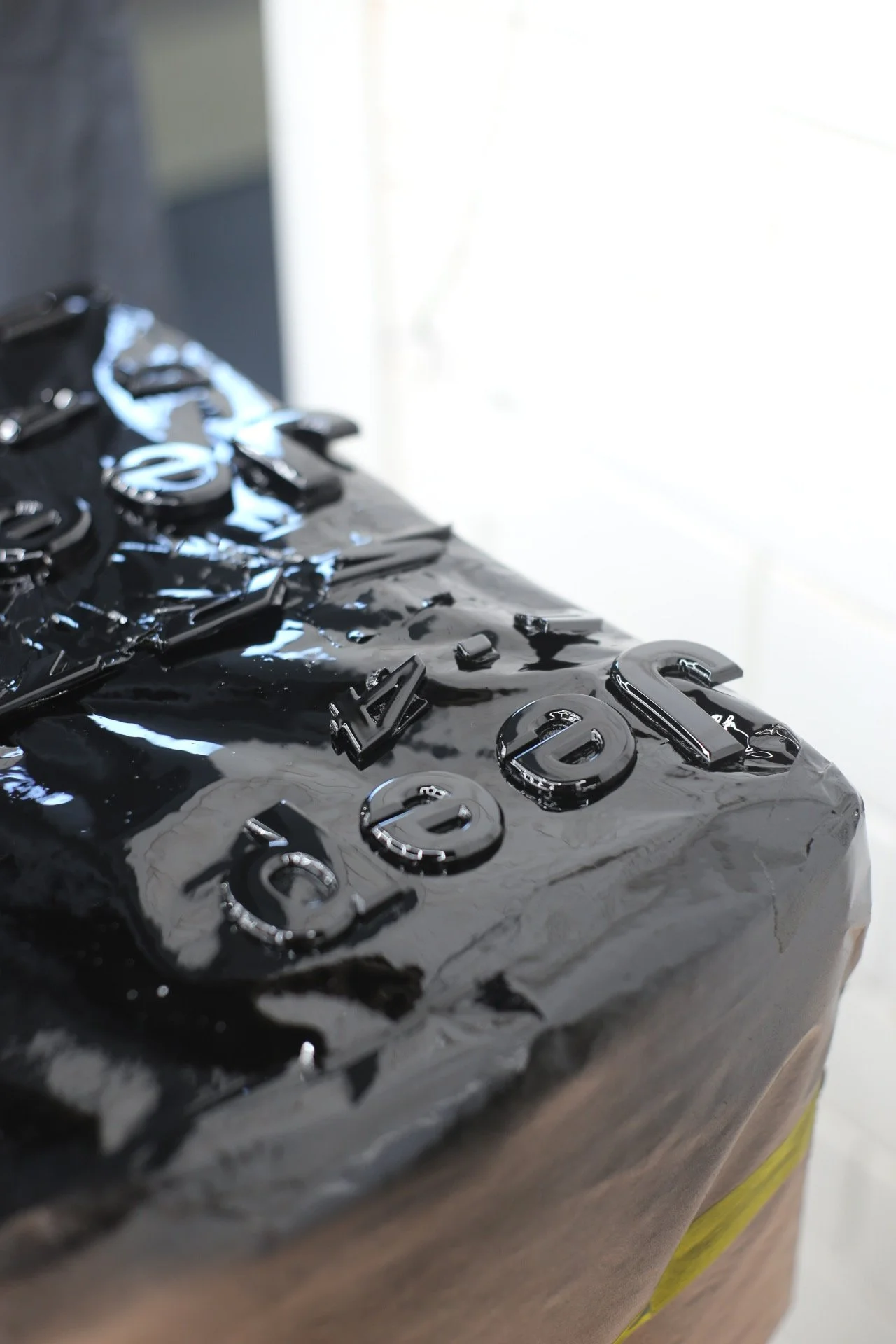 Close-up of black glossy material with raised metallic letters and numbers.
