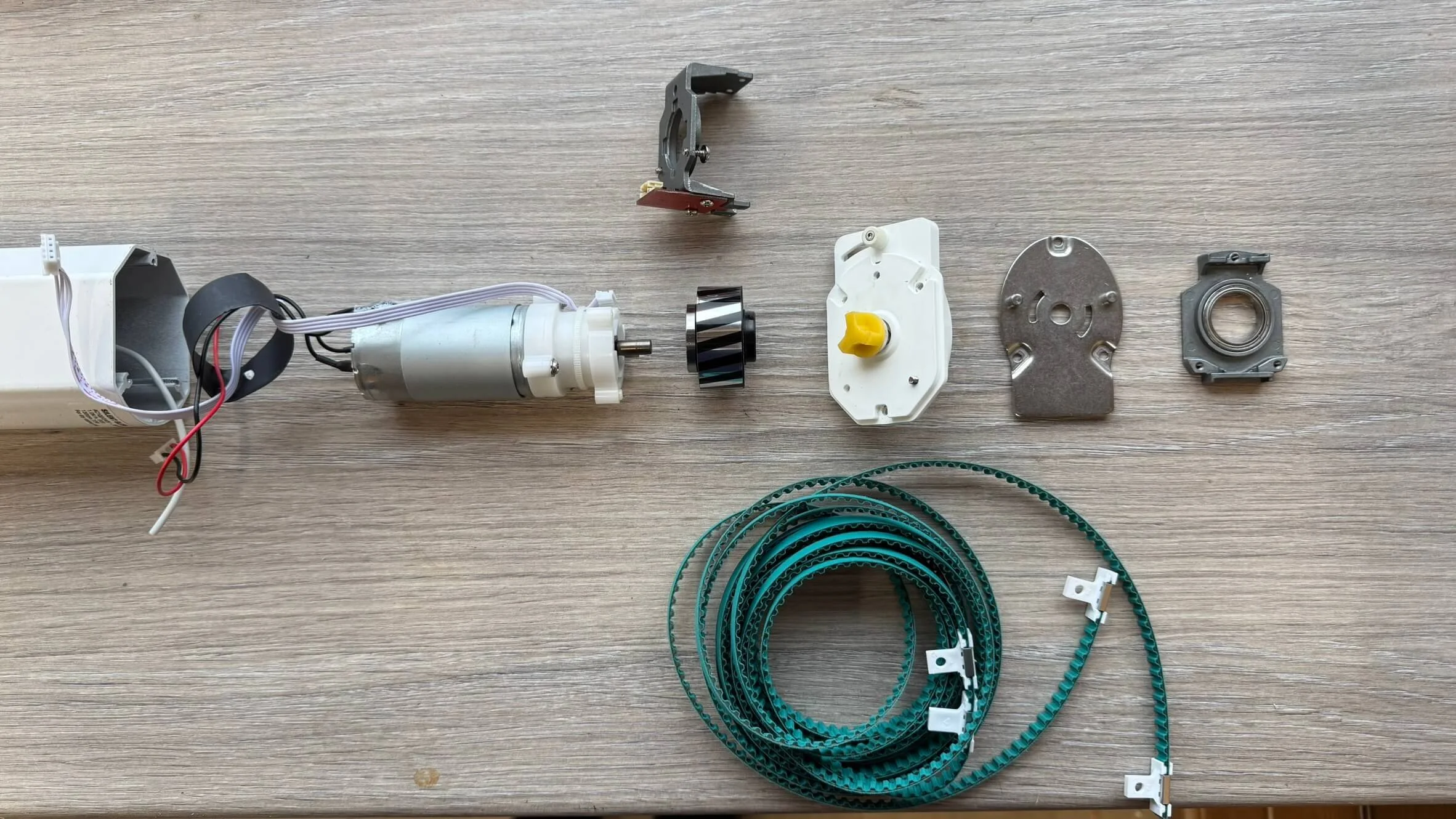 Disassembled electronic device parts, including motors, gears, bezels, belts, and small metal components. Ready for a reverse engineering task