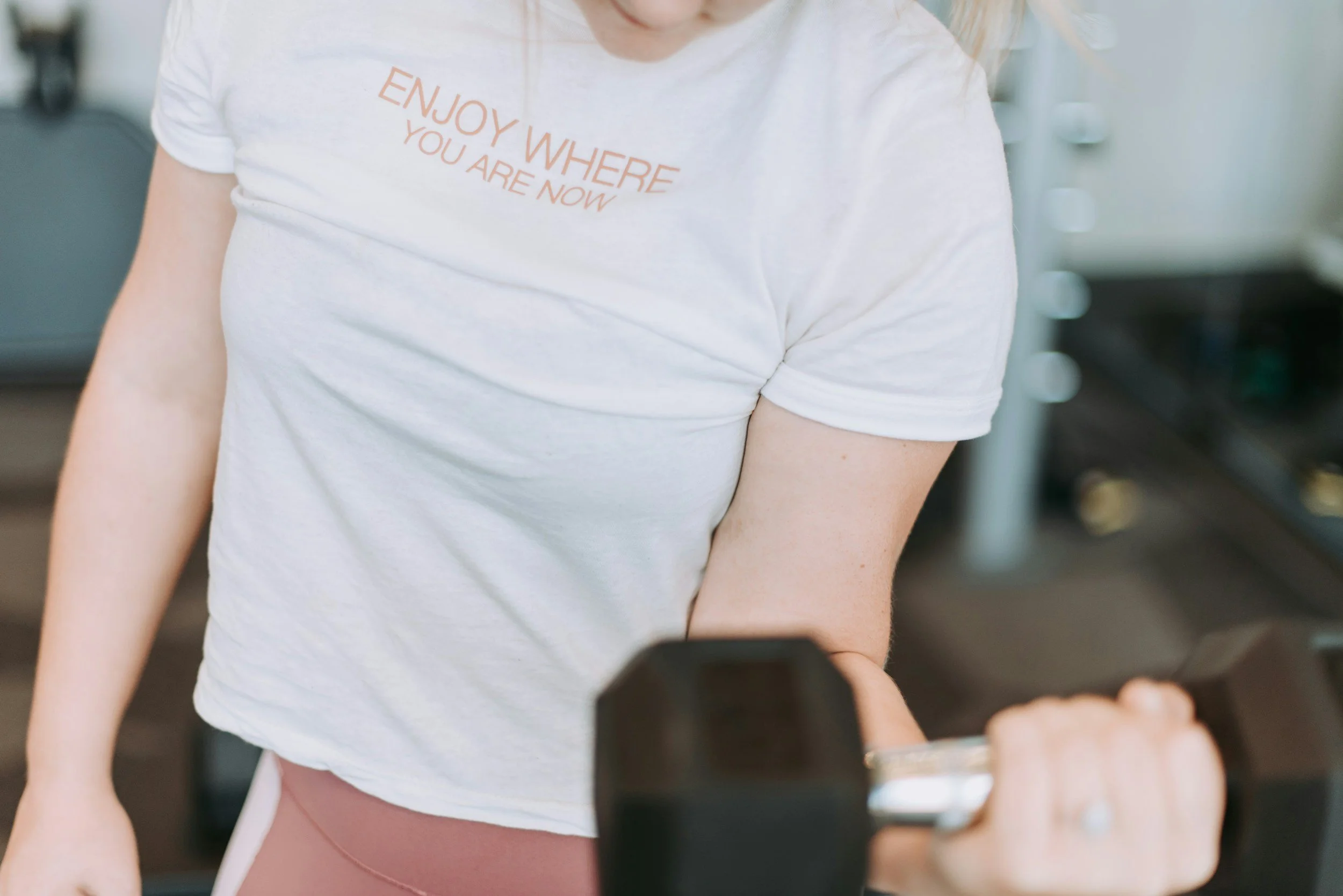 A woman in a white t-shirt lifting a dumbbell