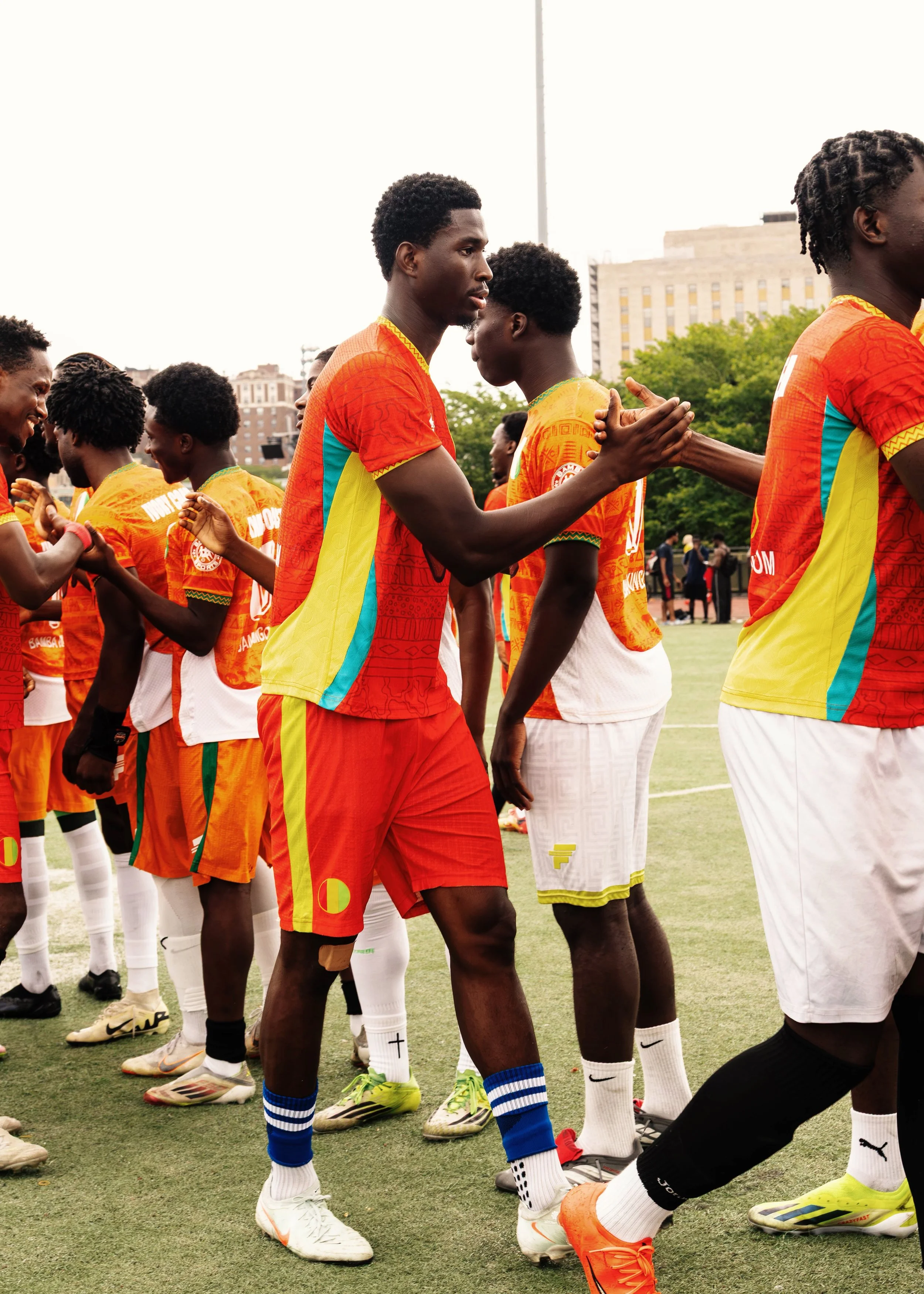 A group of soccer players in colorful uniforms exchanging handshakes on a field.