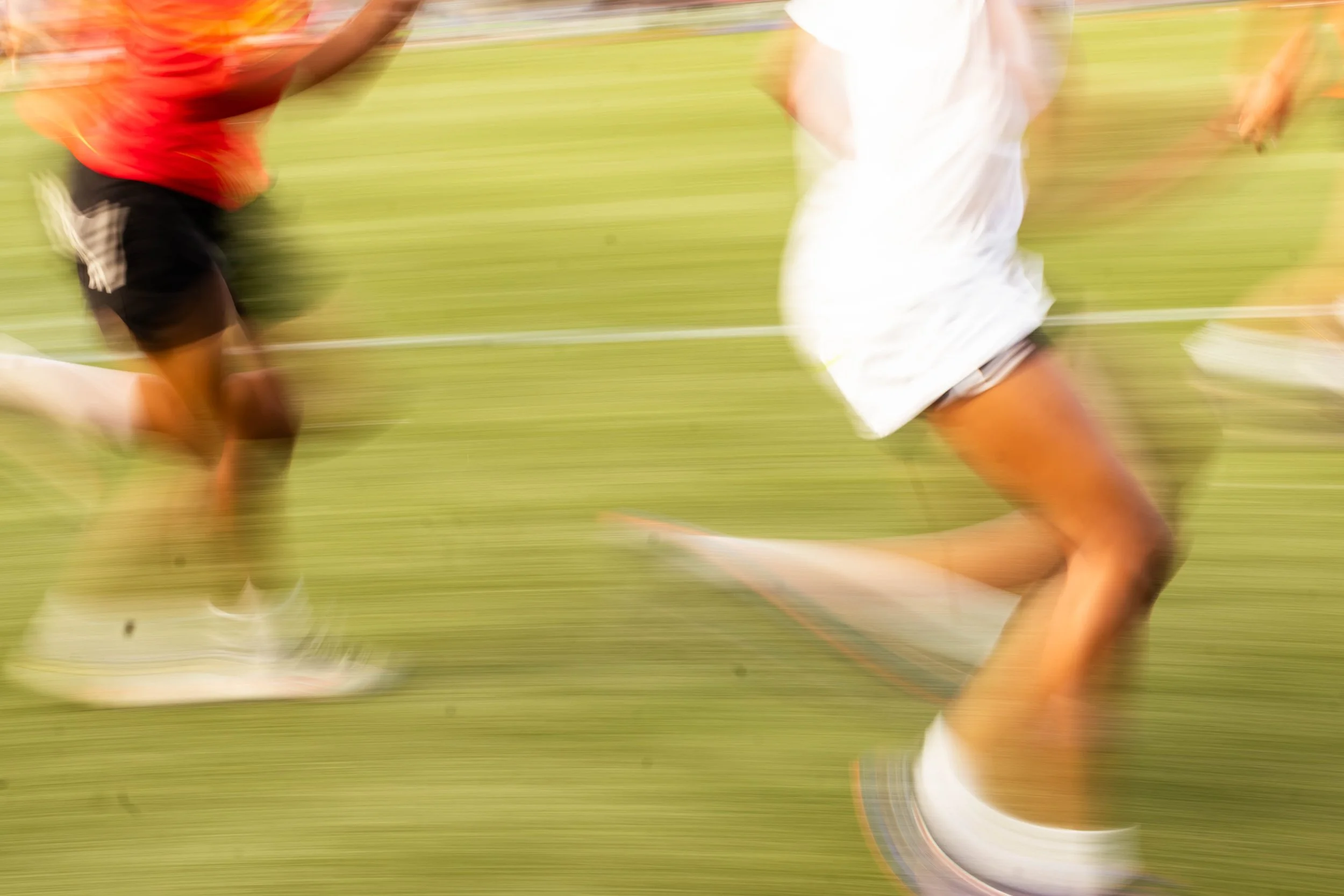 Blurred motion of a soccer game with players running on a grassy field.