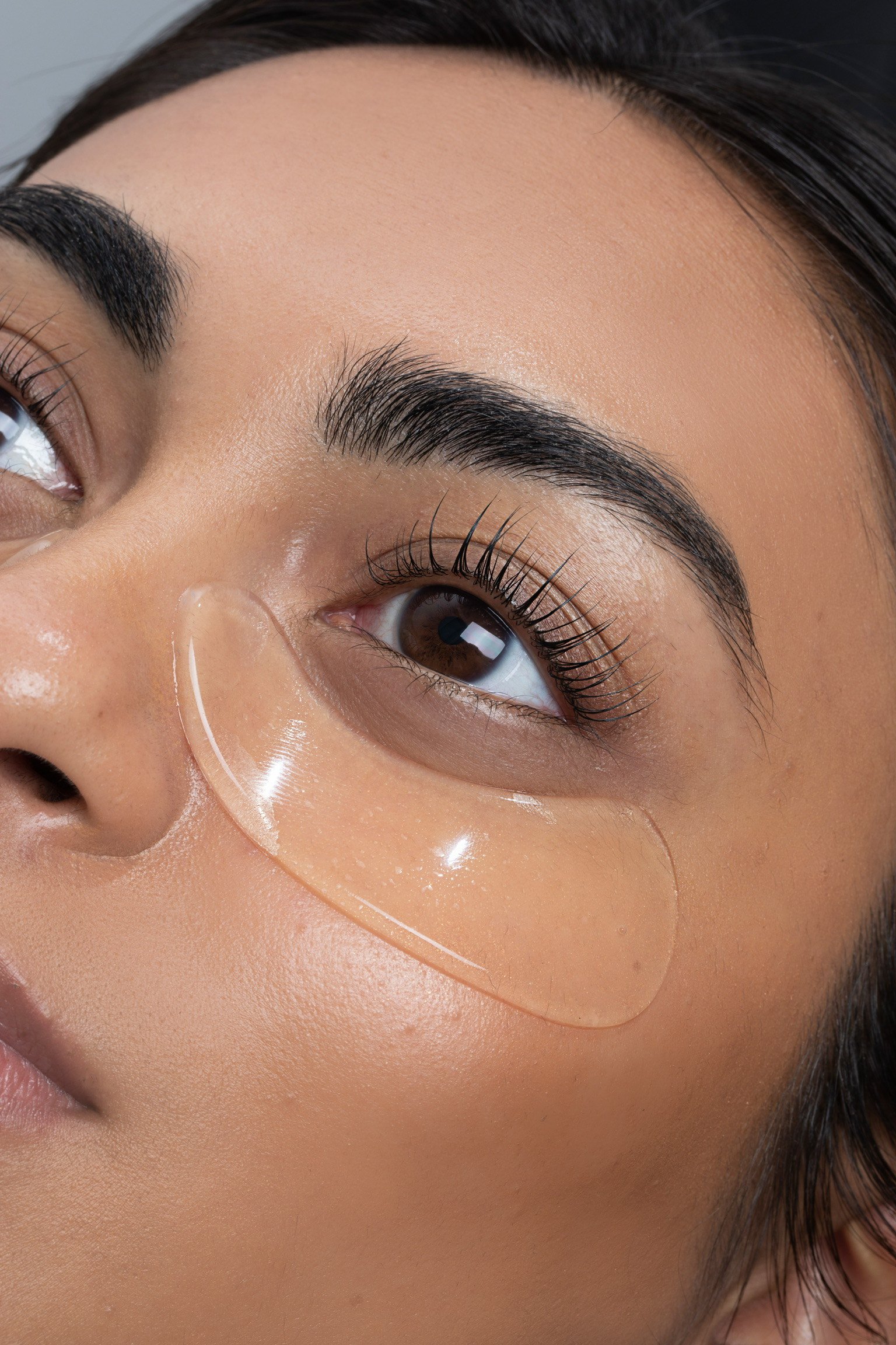 Close-up of a woman's face focusing on her right eye, eyebrow, and part of her nose, with natural makeup and smooth skin.
