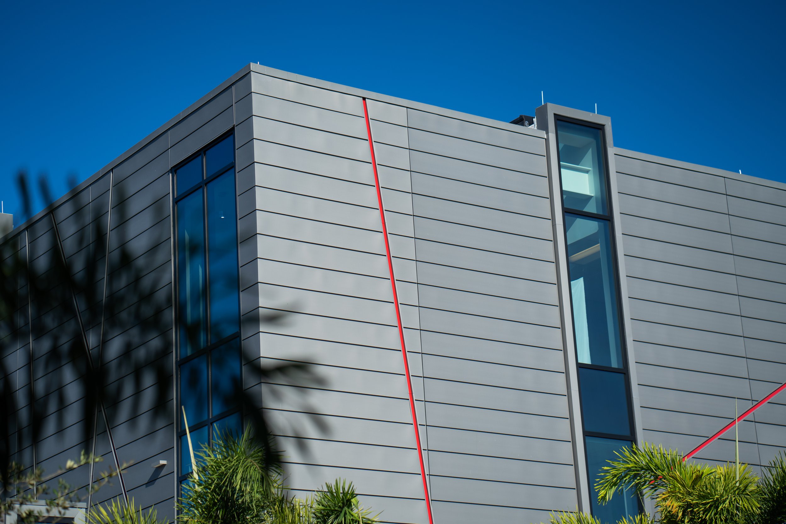 Modern building with gray metal siding, vertical windows, and red accents.