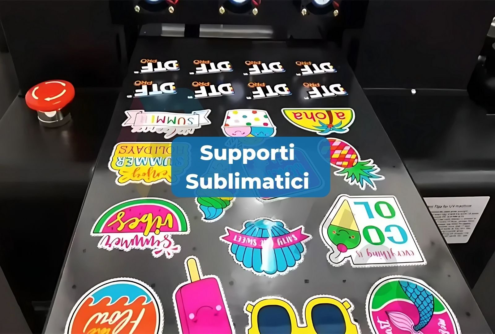 Supporti sublimatici con adesivi colorati e vari, tra cui frutta, personaggi e scritte, con un riquadro blu con la scritta "Supporti Sublimatici" in primo piano.