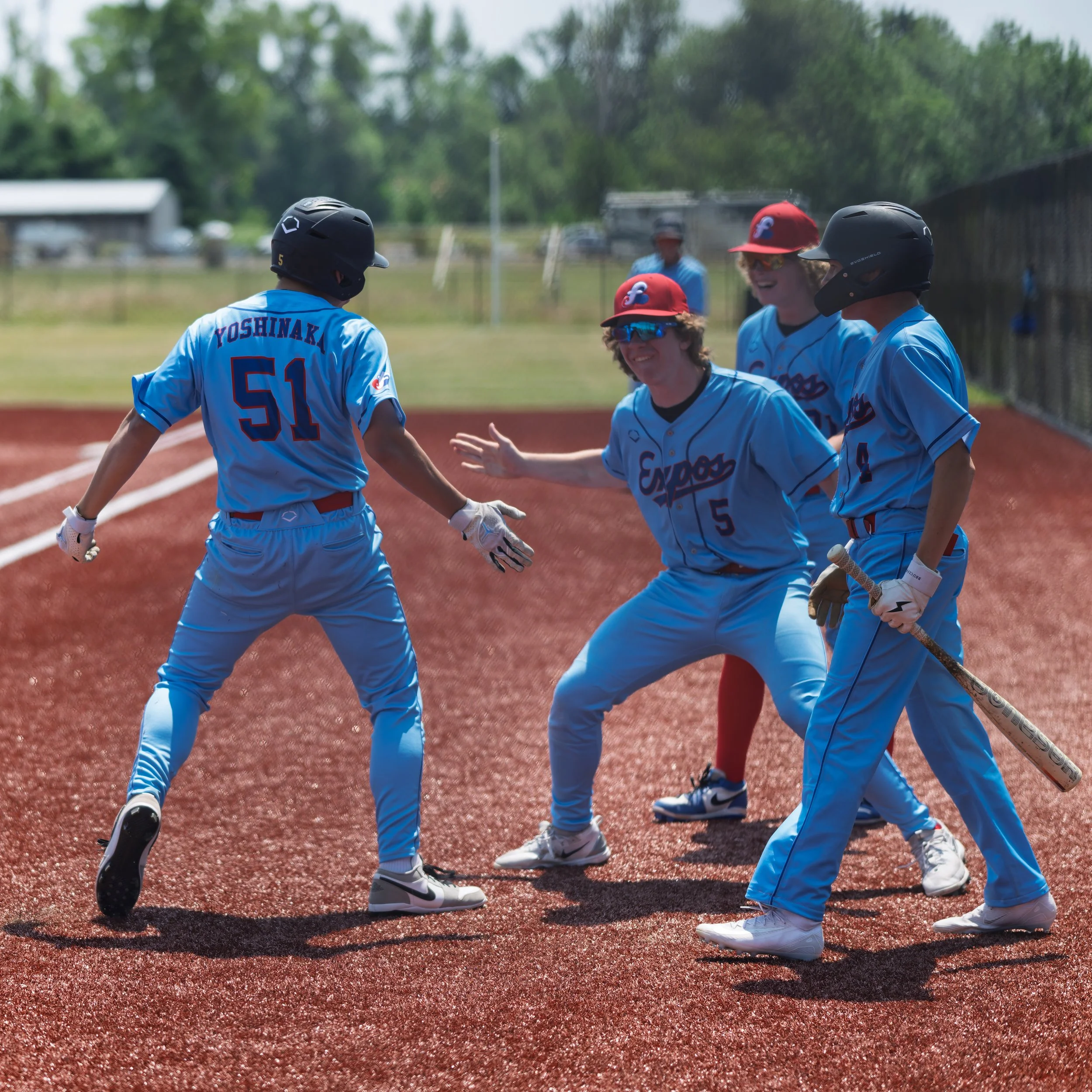 16U baseball teammates celebrating a run during Father's Day tournament game