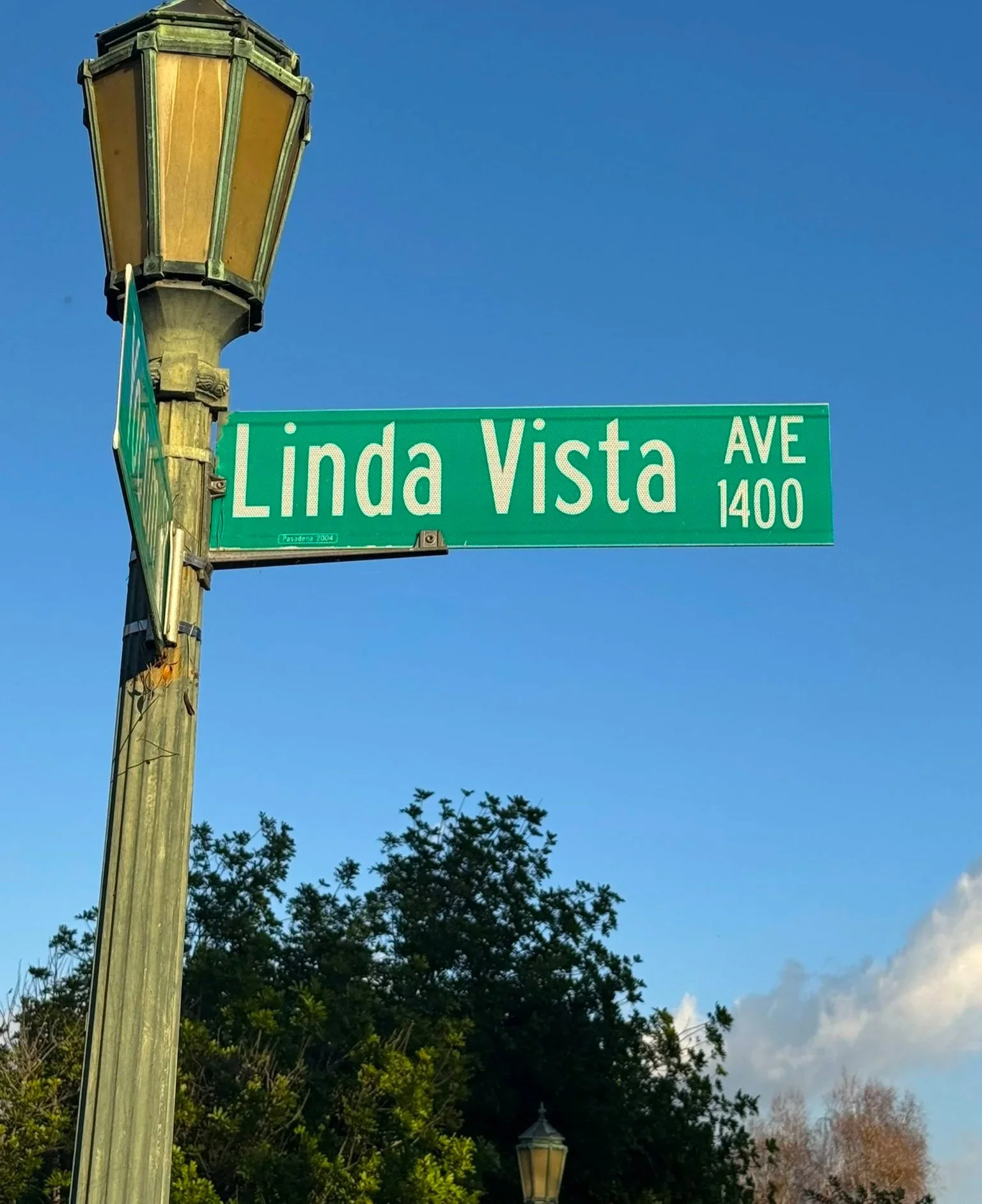 A street sign attached to a lamp post has the street Linda Vista Ave 1400.