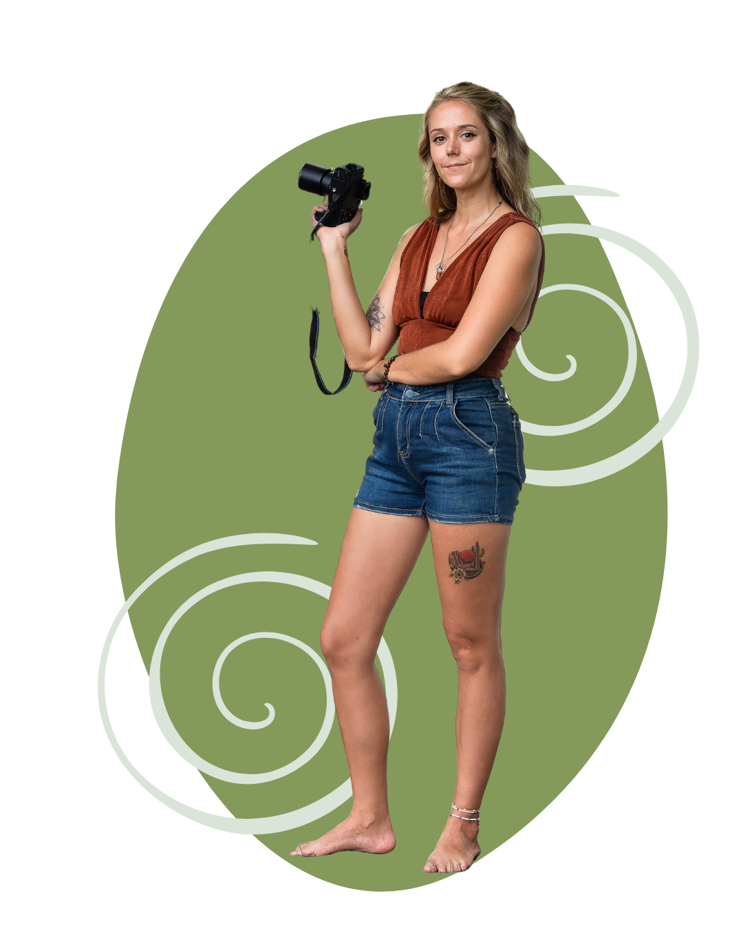 A woman with shoulder-length blonde hair, wearing a sleeveless rust-colored top and denim shorts, holding a camera, standing barefoot with a tattoo on her right thigh, against a green abstract background.