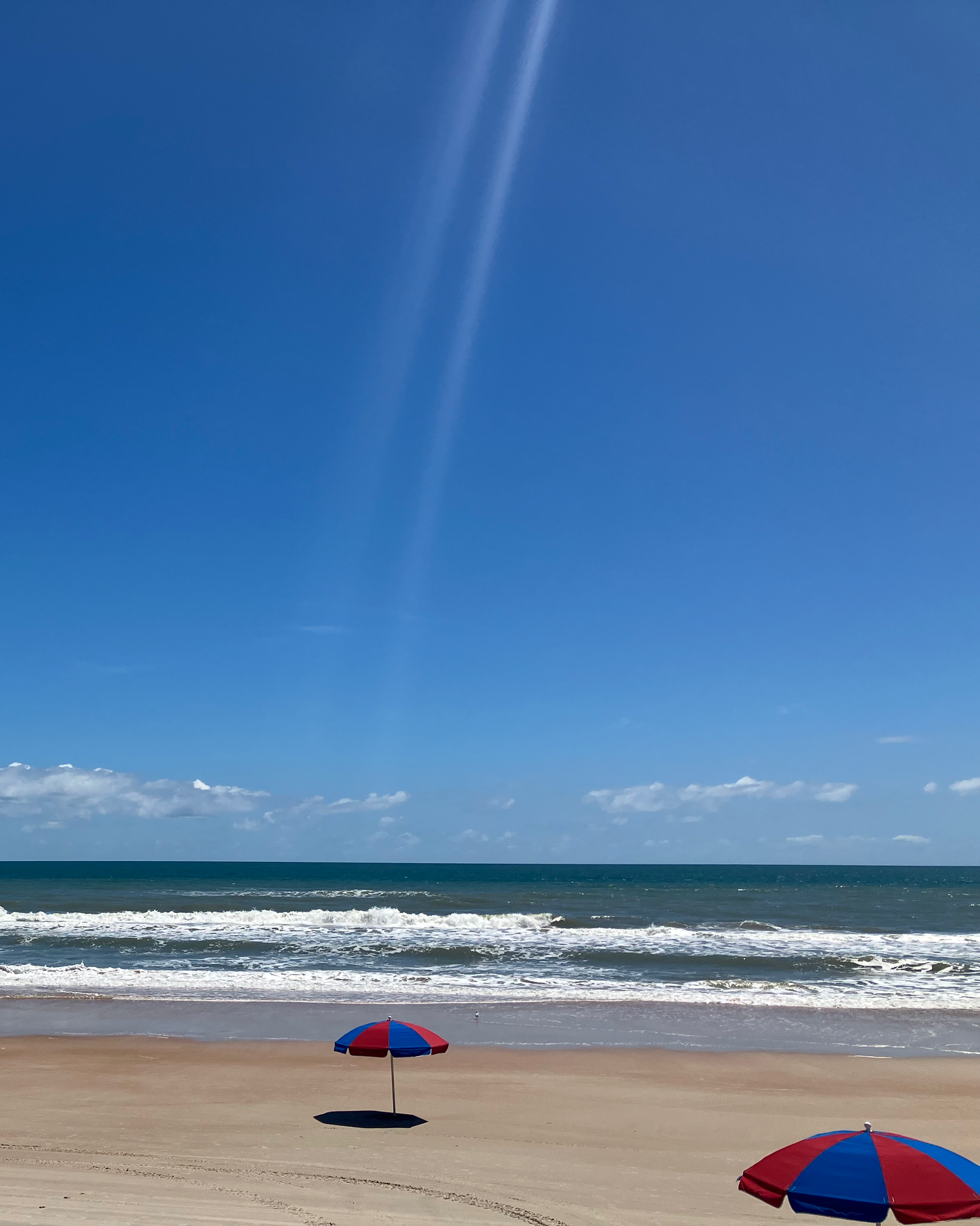 Bue sky, beach waves, colorful umbrellas on Daytona BeachDaytona