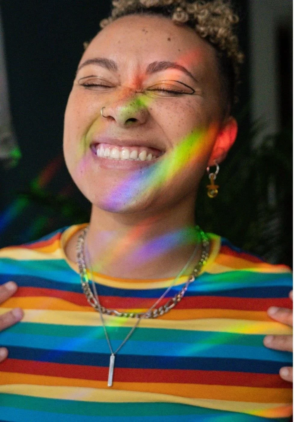 A picture of a queer, BIPOC person smiling in a warm light.