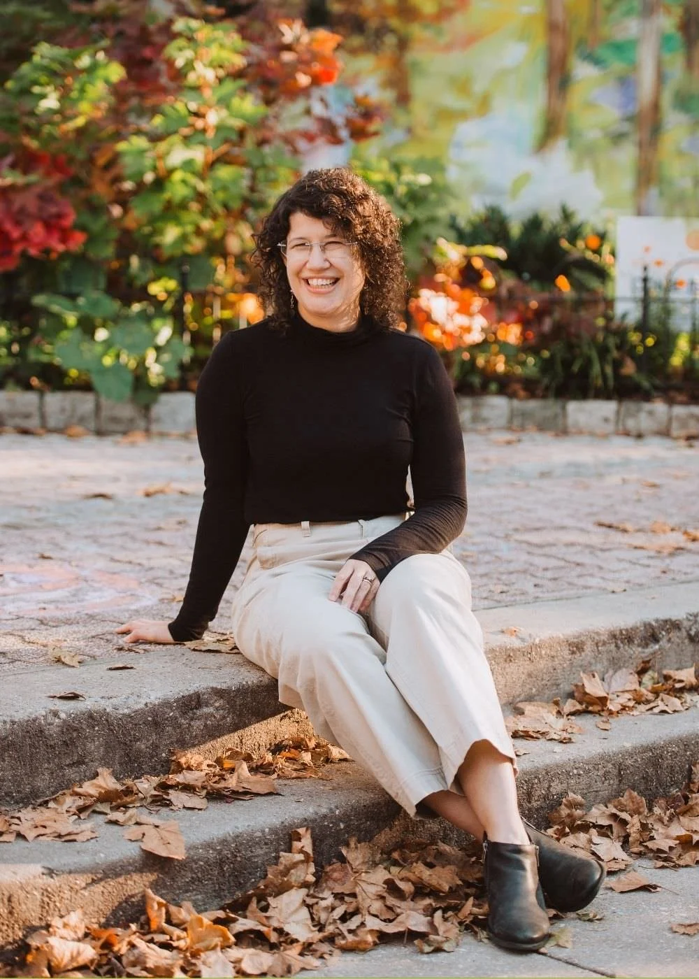 A picture of Christine Ruberti-Bruning ATR-BC, CEDS, LPC, sitting on stairs at Fleisher Art Memorial in Philadelphia, PA.