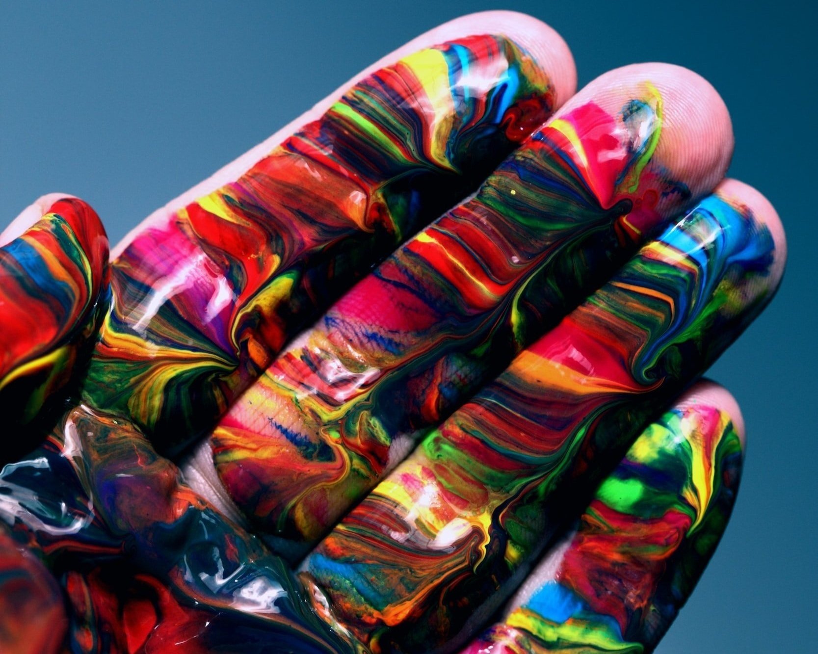 A picture of a hand with swirls of paint on the fingers.